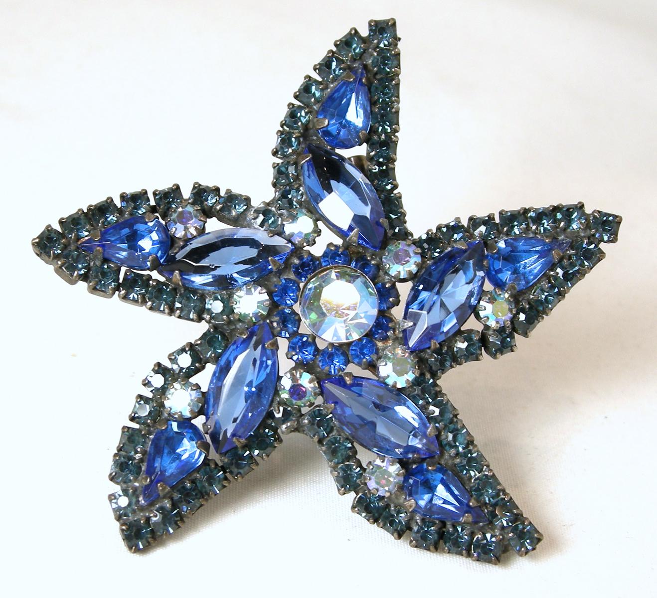 These is a vintage signed Weiss set.  The brooch has a star design with blue crystals and aurora borealis in a silver tone setting.  The brooch measures 2-1/2” across/diameter.  The clip earrings are round and measure 1”.  In excellent condition,