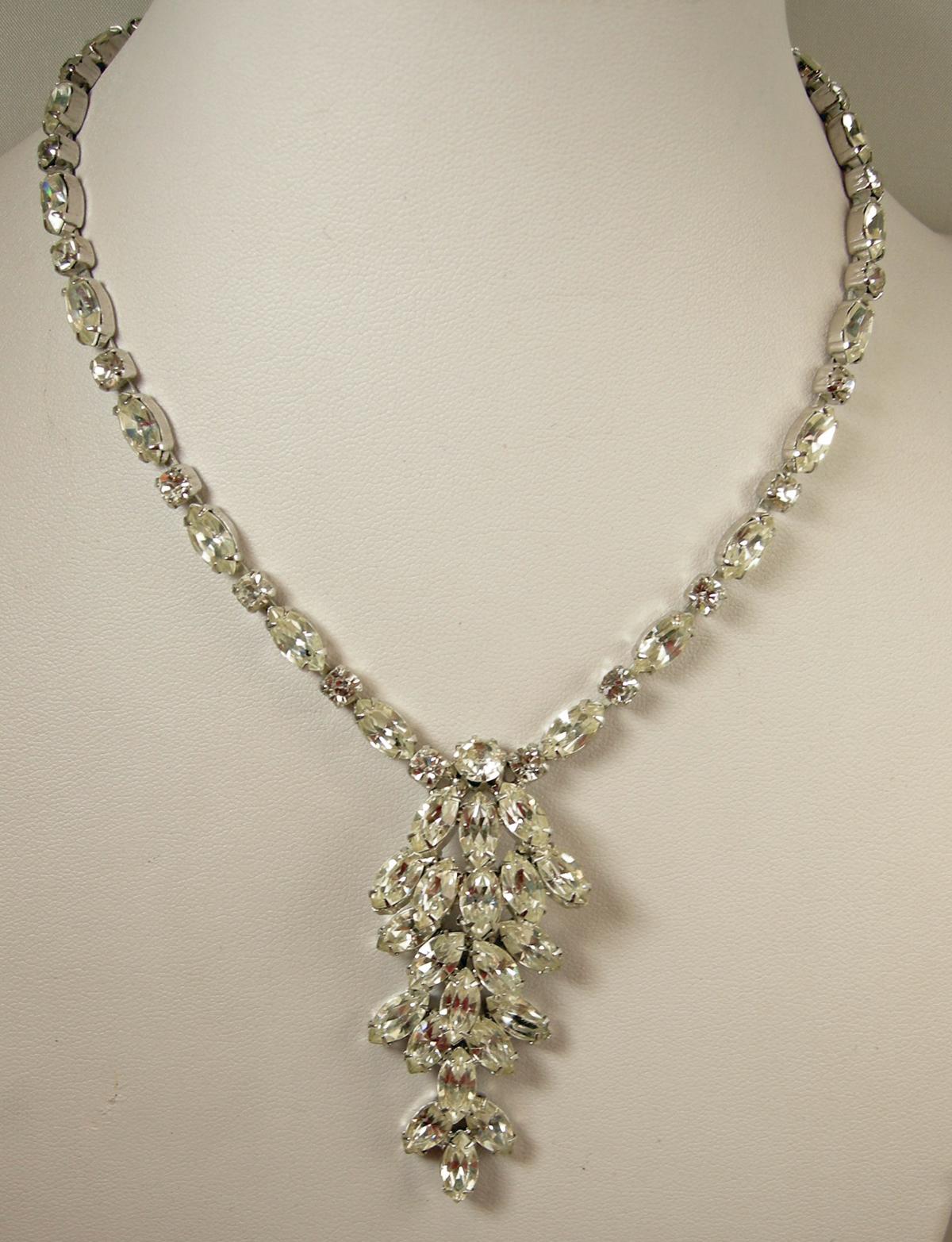 This vintage signed Weiss necklace has a centerpiece of clear crystals overflowing each other. The crystal chain has a hook clasp in a rhodium silver tone finish. It measures 15” and the centerpiece is 2-1/2” x 1”.  This necklace is signed “Weiss”