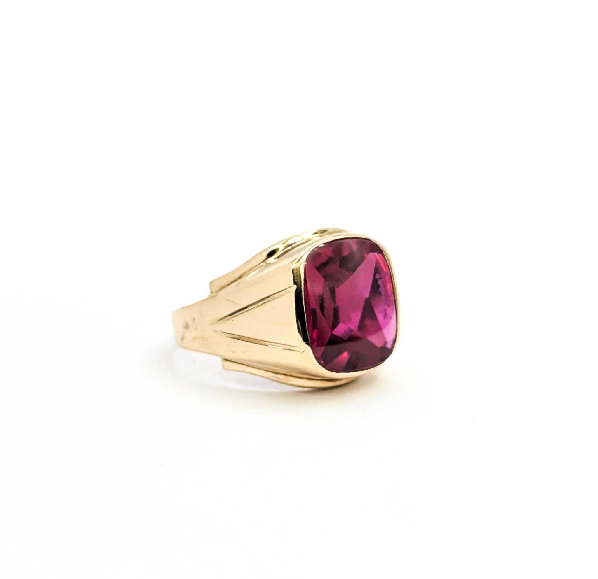 Questo audace anello con sigillo vintage è realizzato in oro giallo 10k e presenta un sorprendente rubino sintetico di 12x14 mm incastonato in un castone. La ricca gemma rossa, con il suo taglio a forma di cuscino, irradia un colore vivido e si fa