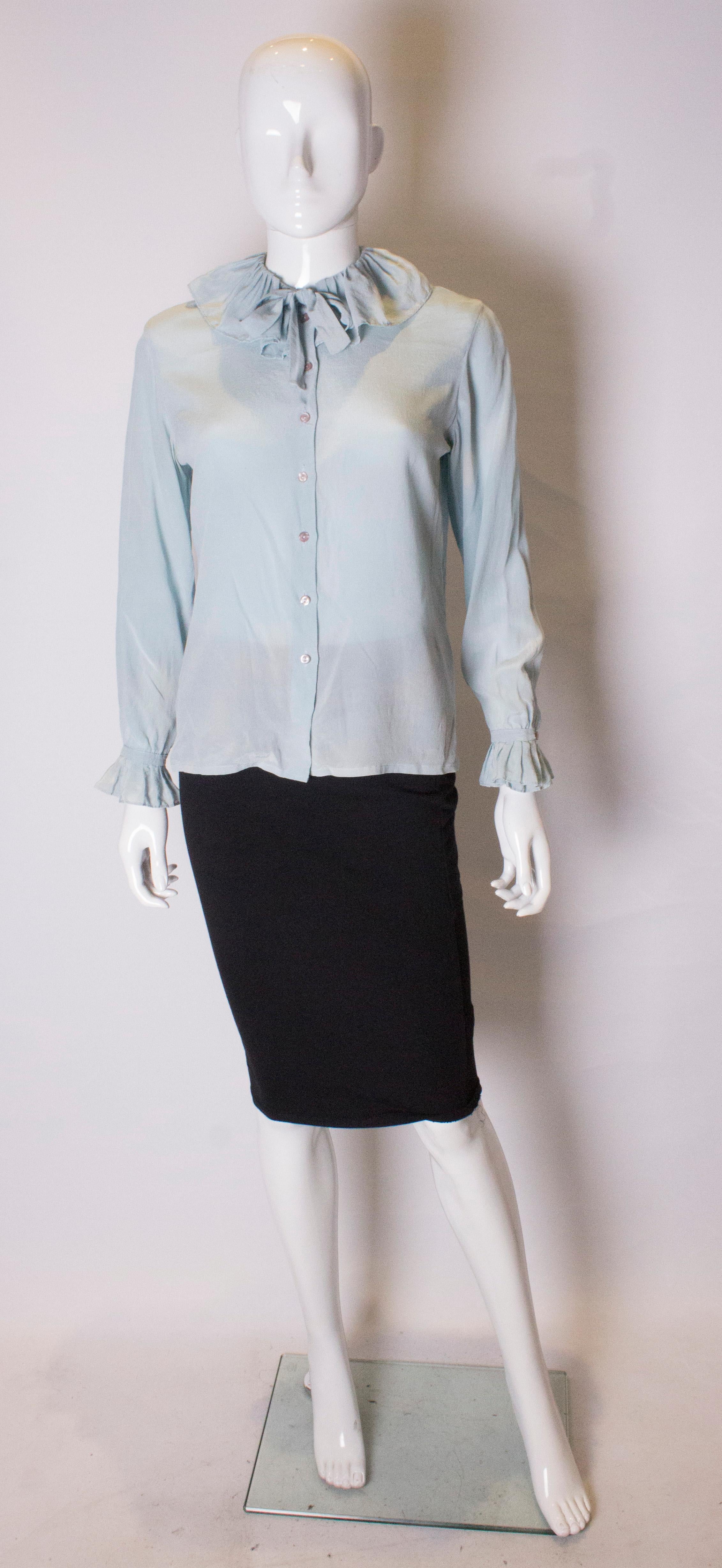 A pretty silk blouse by Dana Cote d'Azur. In a pretty pale blue colour  the blouse has a button front openging and cuffs with a frill neck and short tie .