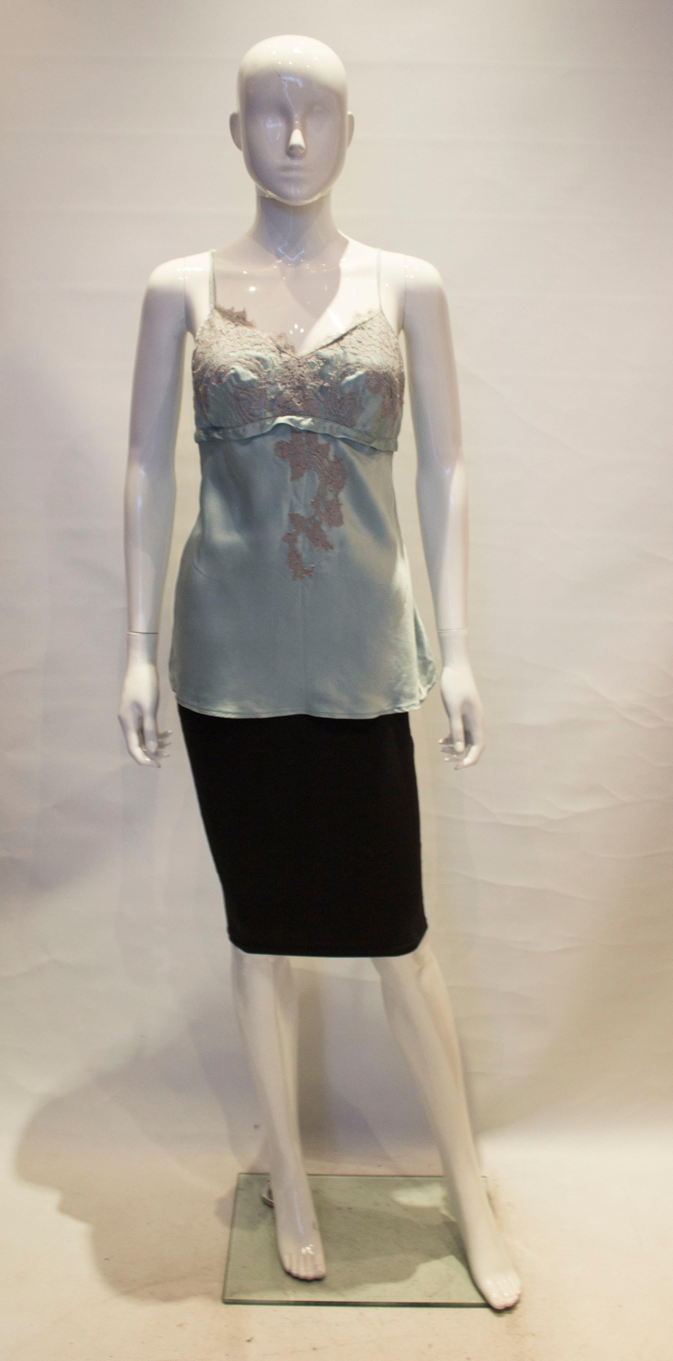 A pretty silk ice blue cami top with lace detail in a lilac /grey colour. The top has a v neckline and back line. 