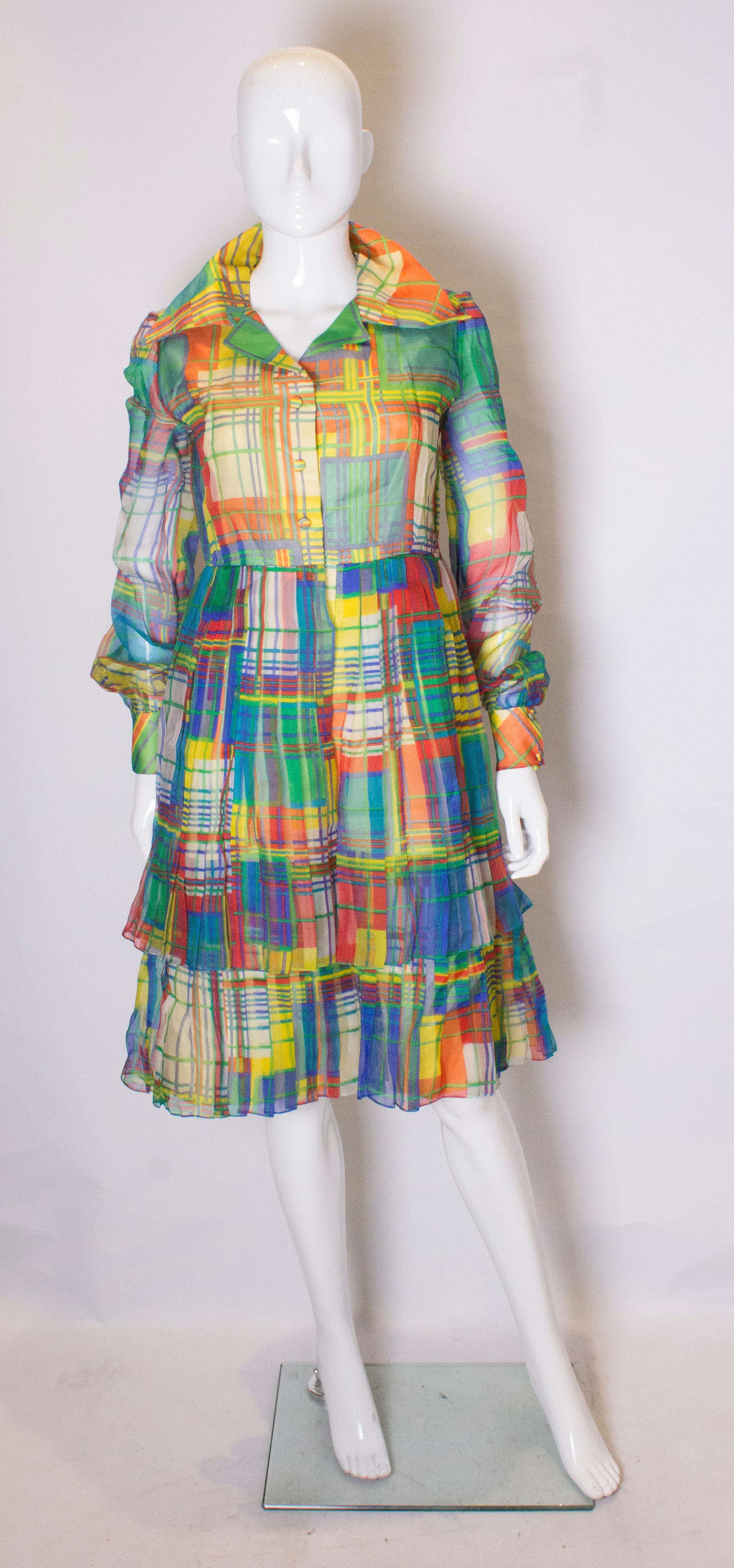 Ein aufsehenerregendes Vintage-Kleid von Nettie Vogue London. Das Kleid ist in einem wunderschönen mehrfarbigen Druck mit Schichten von Falten auf dem Rock. Vorne und an den Manschetten sind Druckknöpfe angebracht.