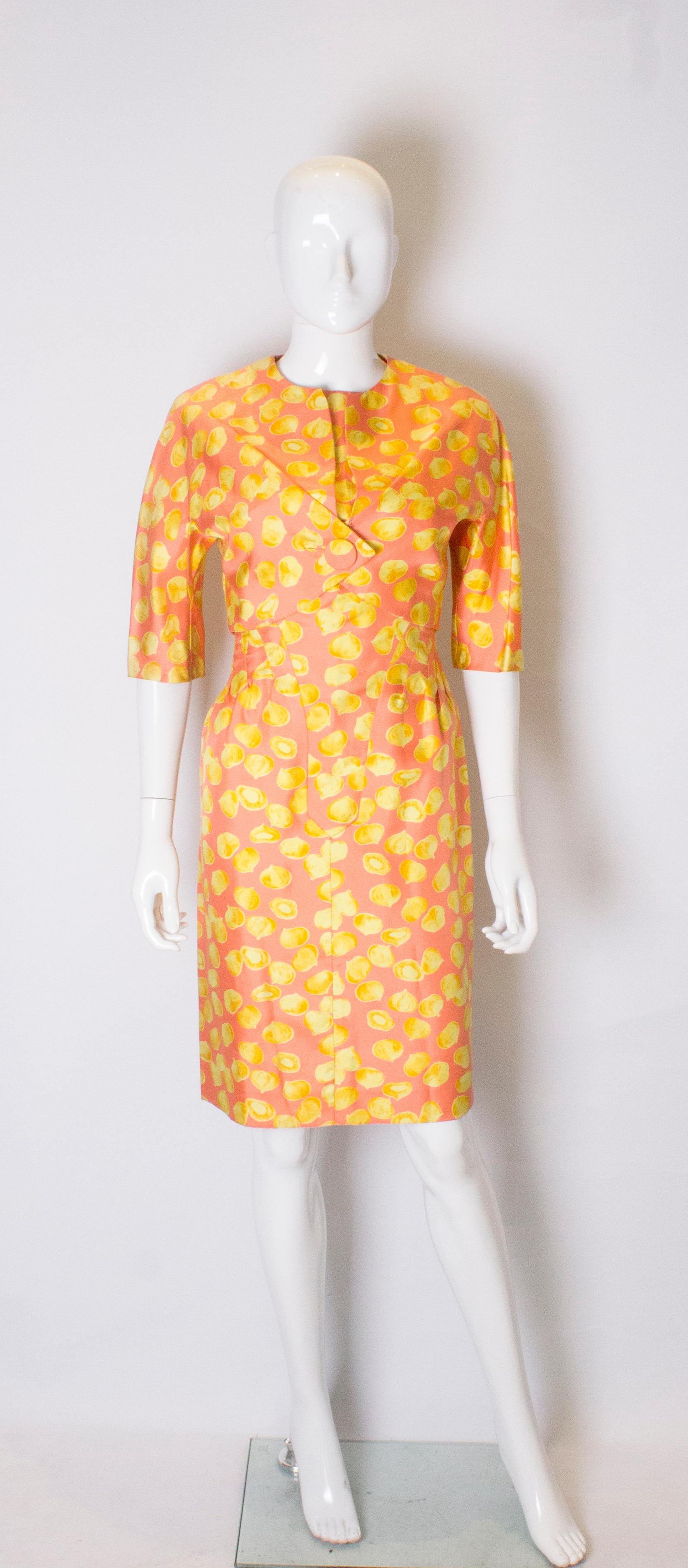 A great silk cocktail dress and jacket in an interesting and unusual garlic print . 
The dress has 11 fabric covered buttons at the front and is tailored with a round neckline. It has a central back zip , 4 '' slit at the hem, and a 4 1/2'' hem.  It