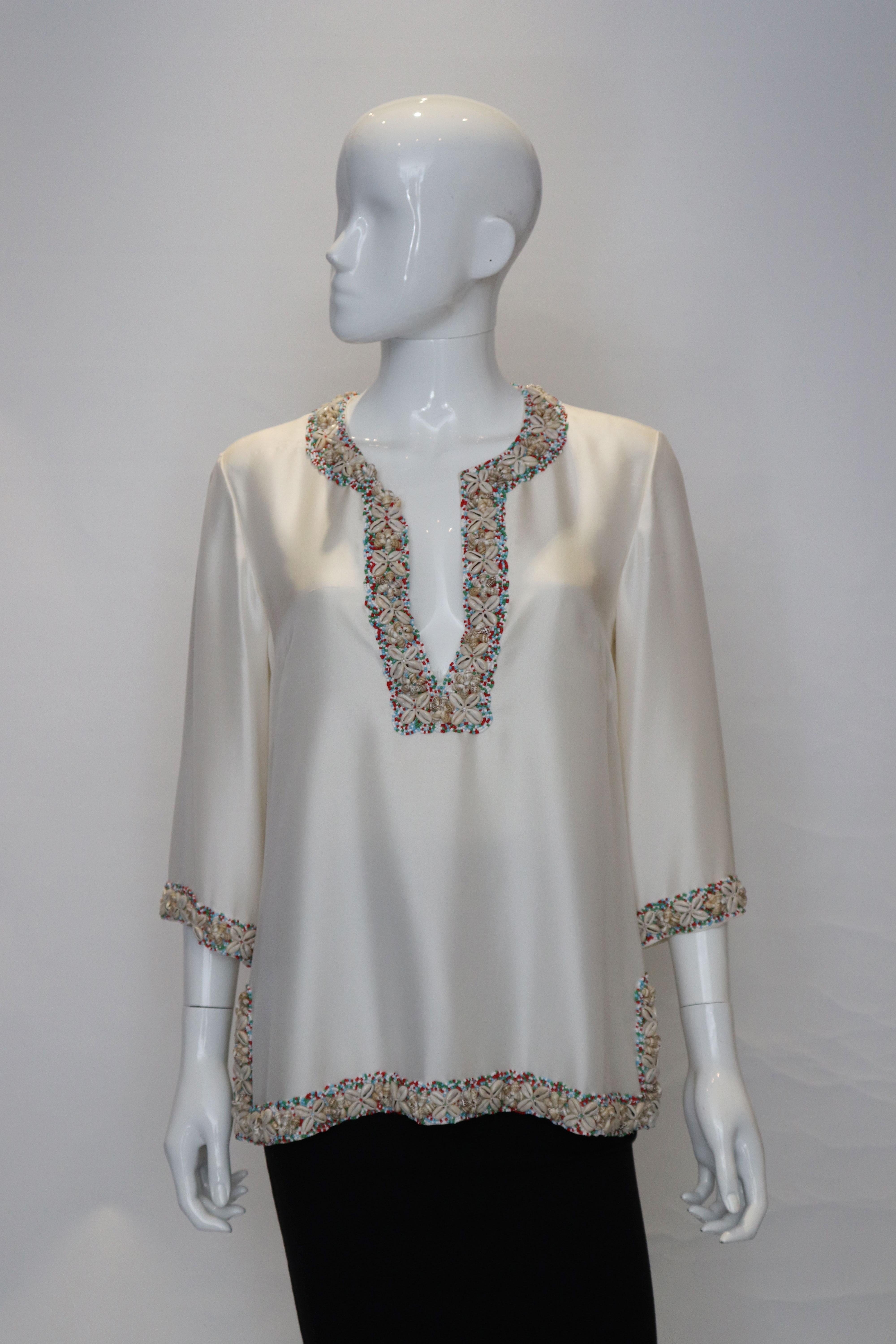 A stunning ivory kafta top with bead and shell decoration.
The kaftan is lined in silk and has 4'' slits on either side. It has a round neckline with a central opening with hook and eye fastening. It is quite heavy .