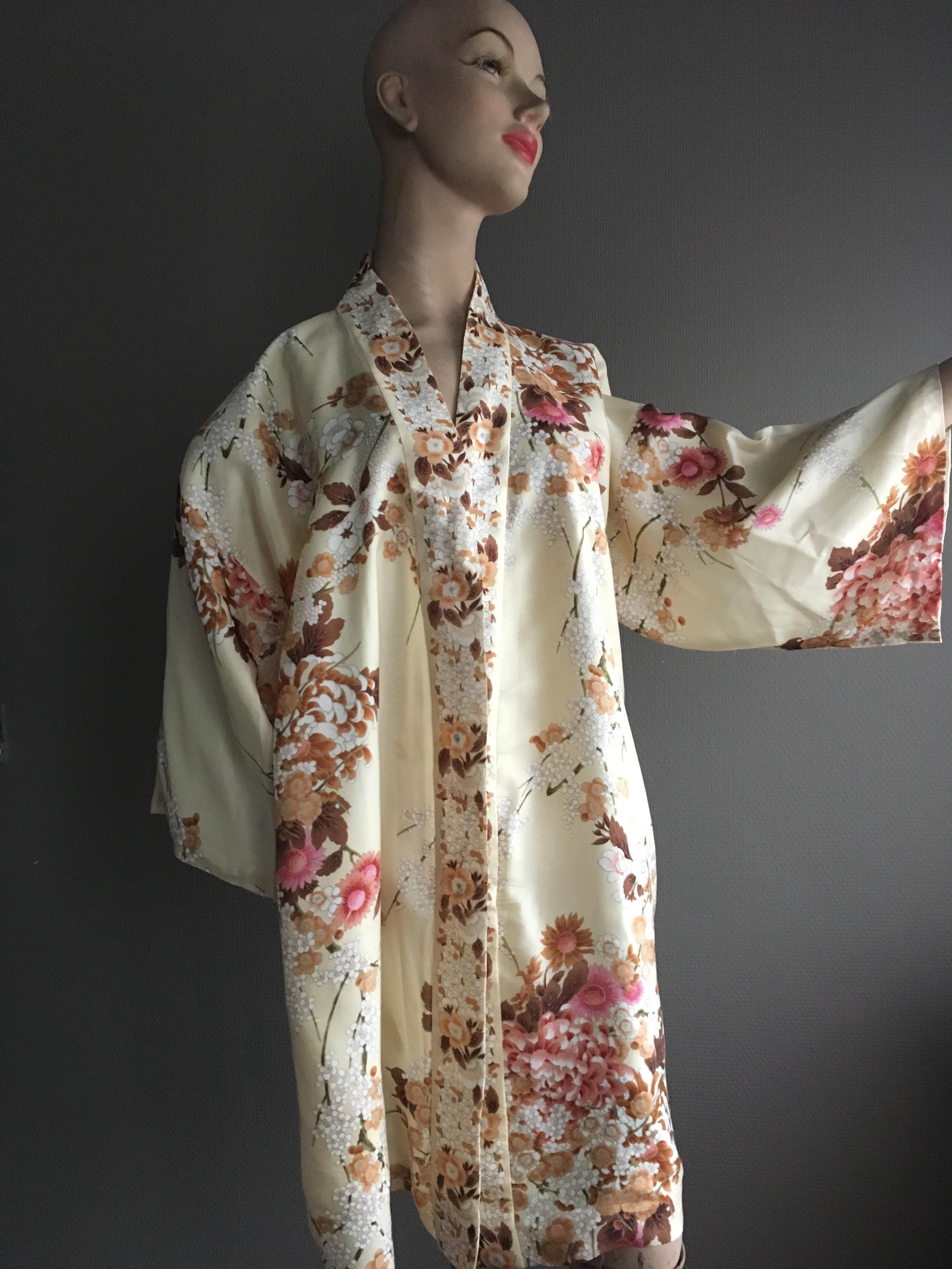 Beautiful silk Kimono designed and executed in Japan in the sixties, printed with the floral motifs of the Japanese cherry and chrysanthemums,soft tones, lined on the inside, 
closes with metal push buttons and a matching hip band.