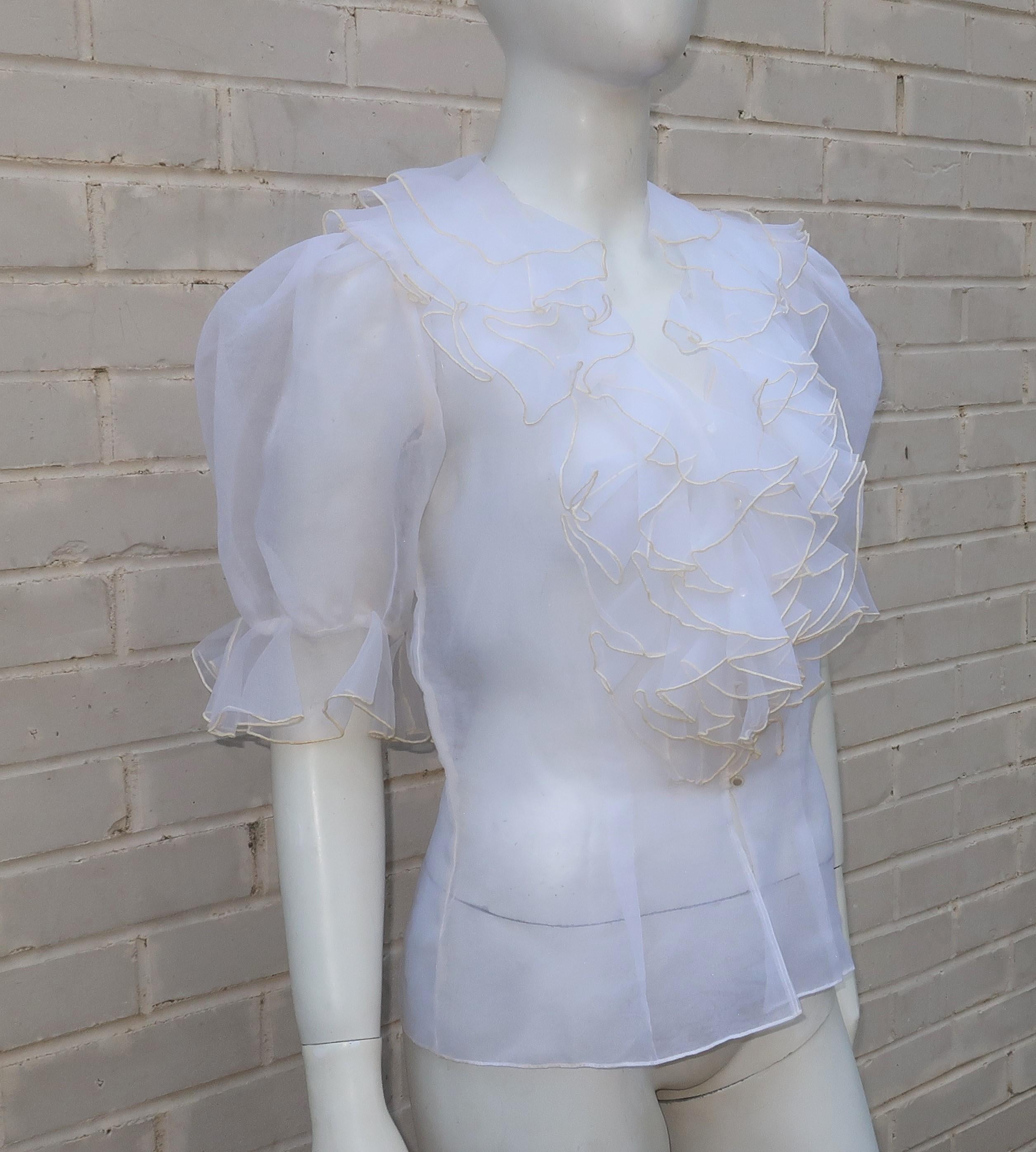 An ultra feminine off-white silk organza blouse with lovely details including layers of ruffles at the neckline, delicate mother-of-pearl buttons and puffed sleeves.  It buttons at the front with darting through the torso to add shape and nip the