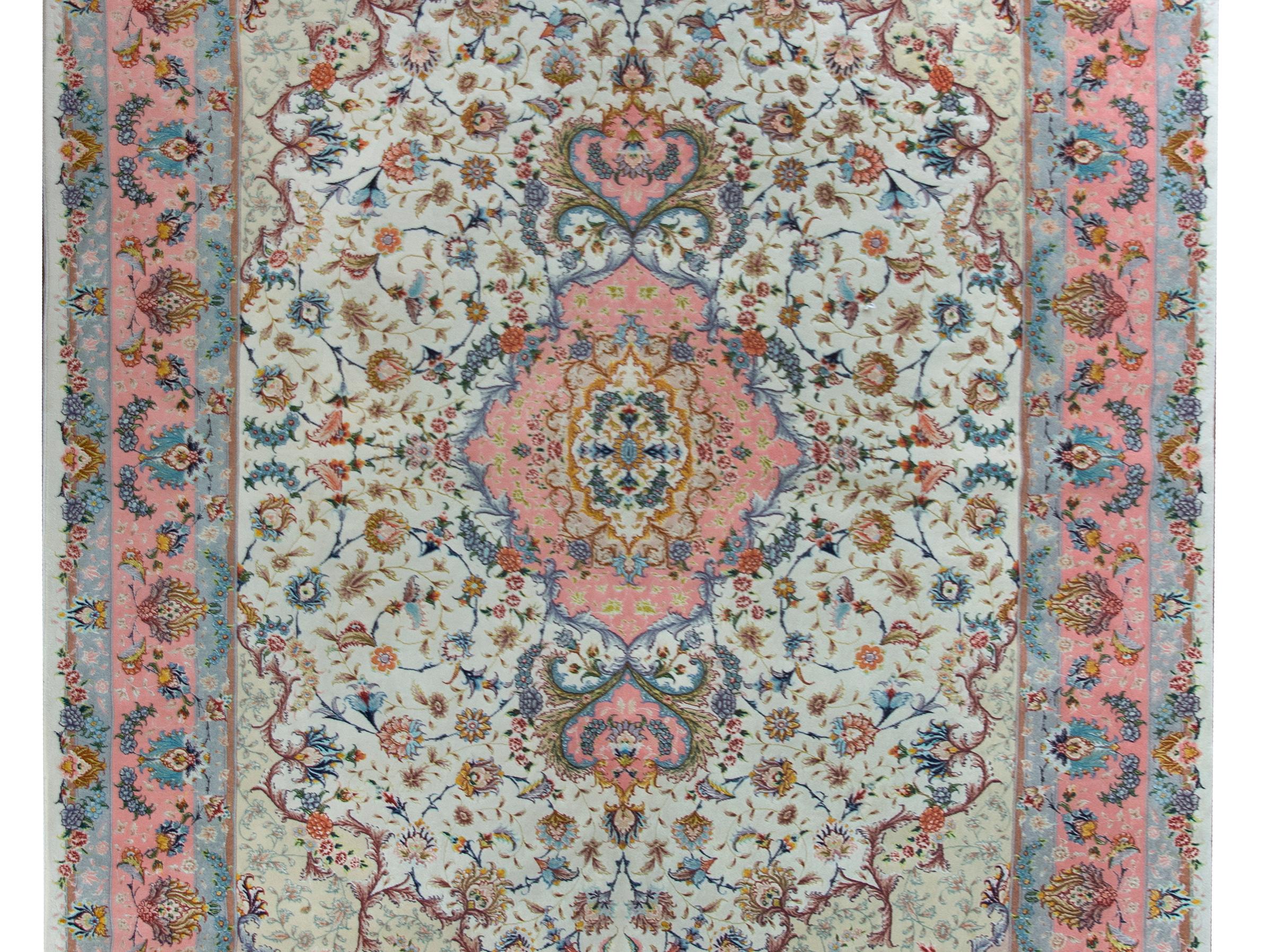 A remarkable late 20th century Persian Tabriz hand-knotted silk and wool rug with a mesmerizing pattern with a central medallion living amidst a finely rendered field of scrolling vines and flowers, and surrounded by a wide large-scale repeated