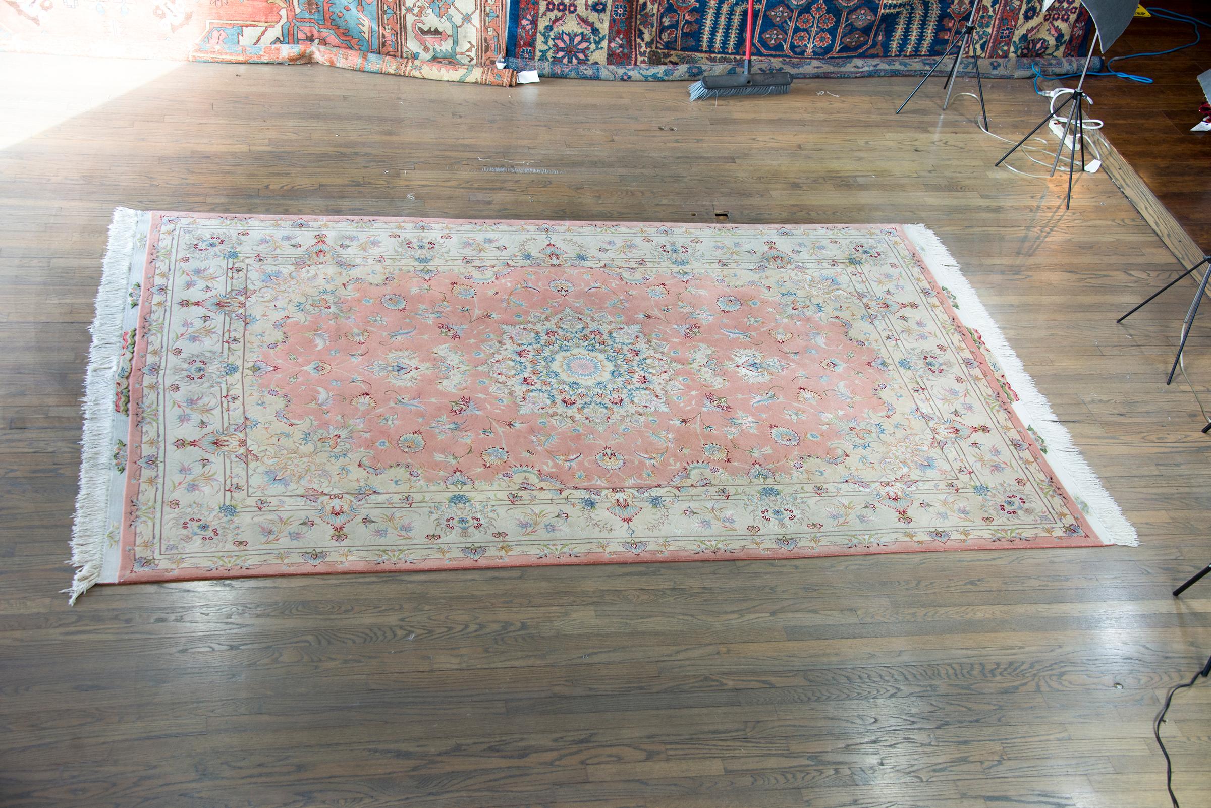 A remarkable late 20th century Persian Tabriz hand-knotted silk and wool rug with a mesmerizing pattern with a central medallion living amidst a finely rendered field of scrolling vines and flowers, and surrounded by a wide large-scale repeated