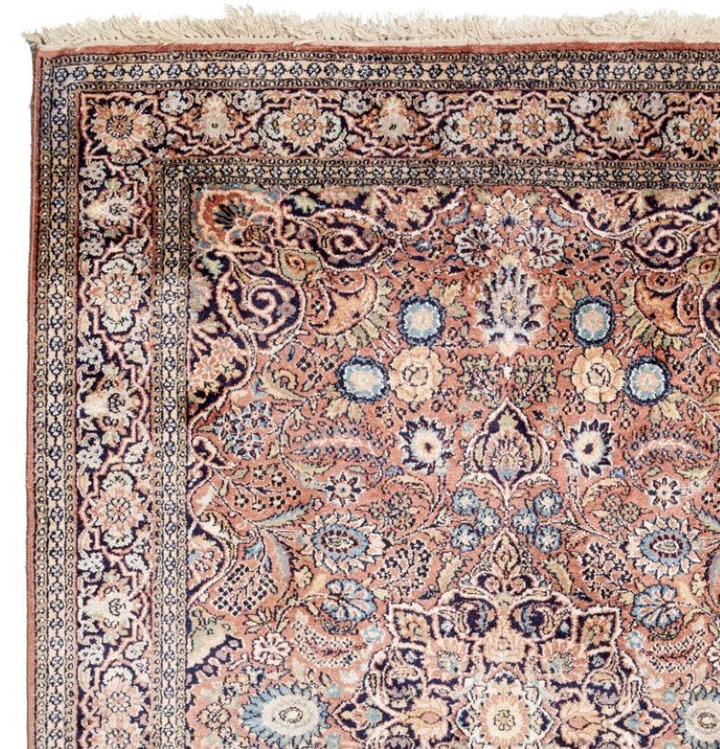 20th century, India, a finely knotted silk Kashmir rug with, floral designs incorporating blues, greens, and neutrals on a light pink ground. There is a label remnant verso. Because of the high sheen, some portions of the rug seem darker than