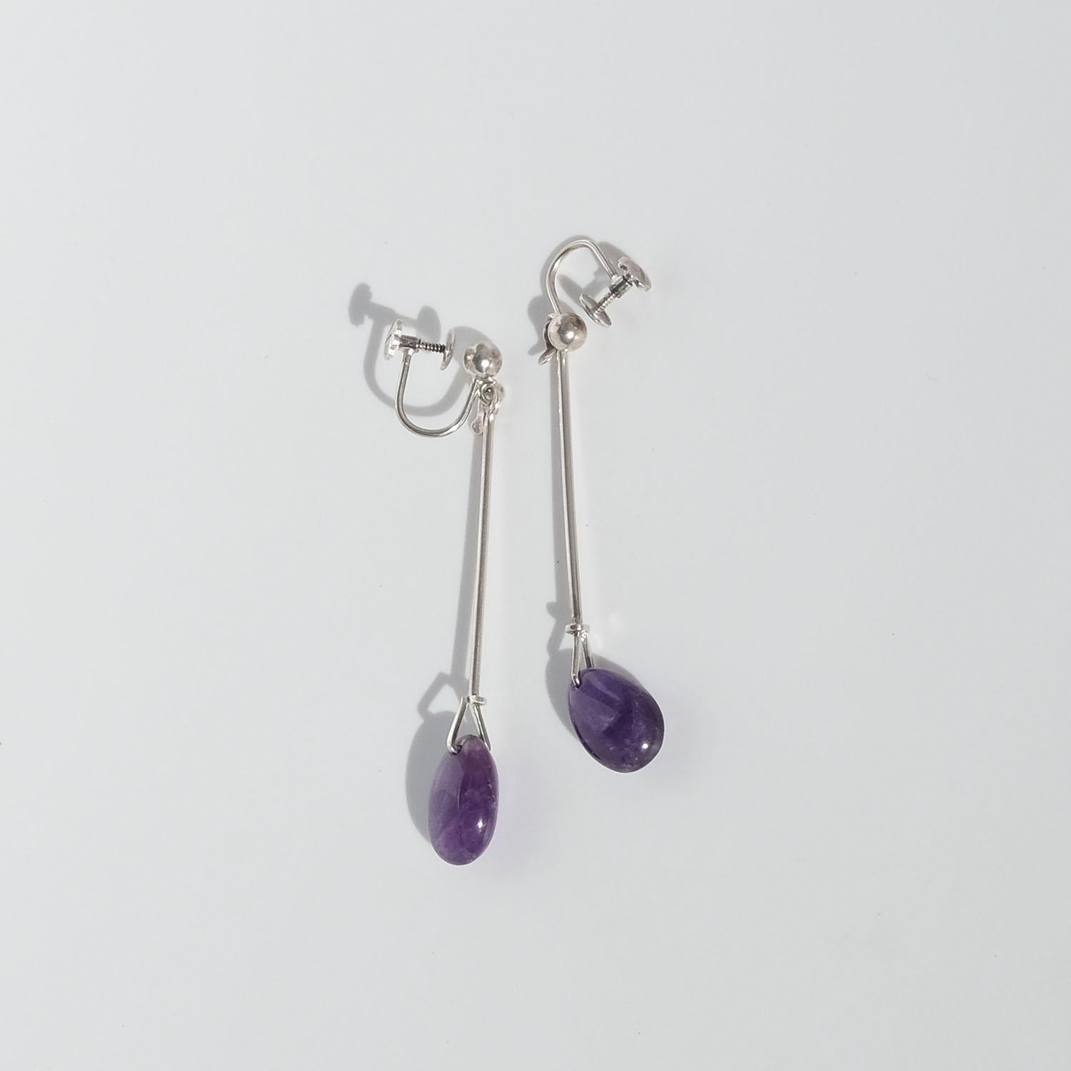 These silver earrings are adorned with teardrop shaped amethysts which dangle beautifully along its wearer's neck. The earrings are part of Vivianna Torun Bülow-Hübe's world known collection Dew Drop, which she designed in the mid 1950s; a
