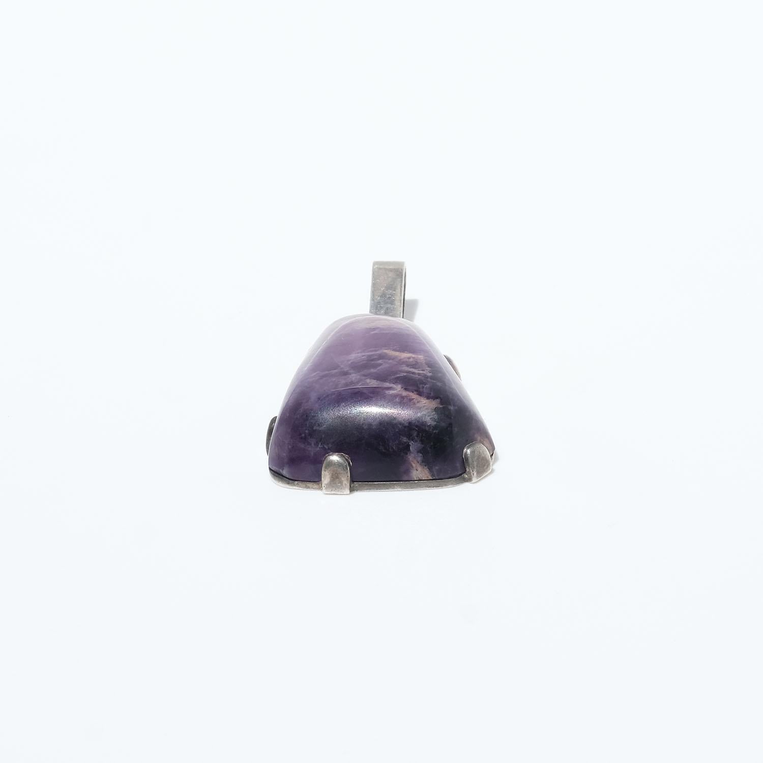 This pendant has an amethyst quartz with a cabochon, free formed cut. The setting and the bail is made of silver.

The pendant is perfect for any social event as well as for the everyday wardrobe. 

Dimensions: amethyst wd./ht. 20/28, wt. 12 gm
