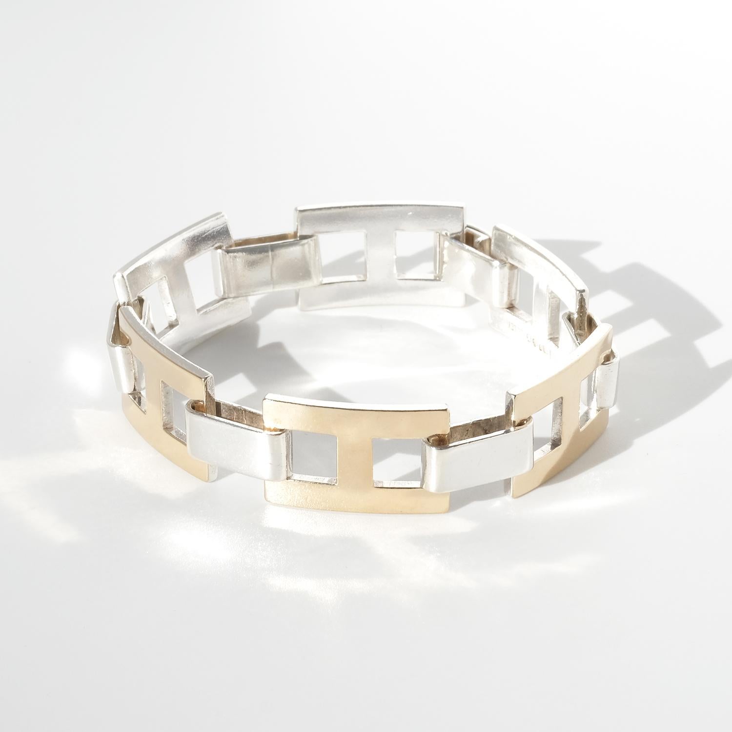 This silver bracelet is composed of silver rectangles connected to each other with wide silver links. Every link has a thin gold plate on the silver. The bracelet secures easily with a folding clasp.

The design of the bracelet allows it to slide