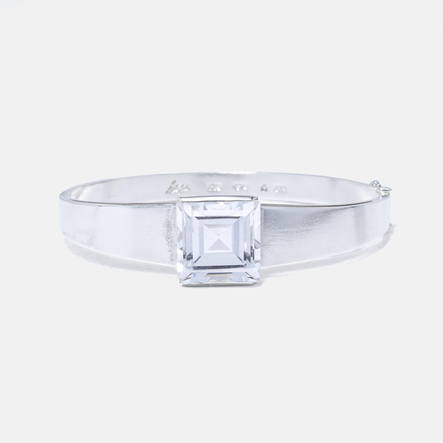 This silver bracelet features a classic design that seamlessly integrates with the inherent beauty of the faceted, square rock crystal centerpiece.

Elevate your collection with a piece that transcends trends, telling a story of craftsmanship,