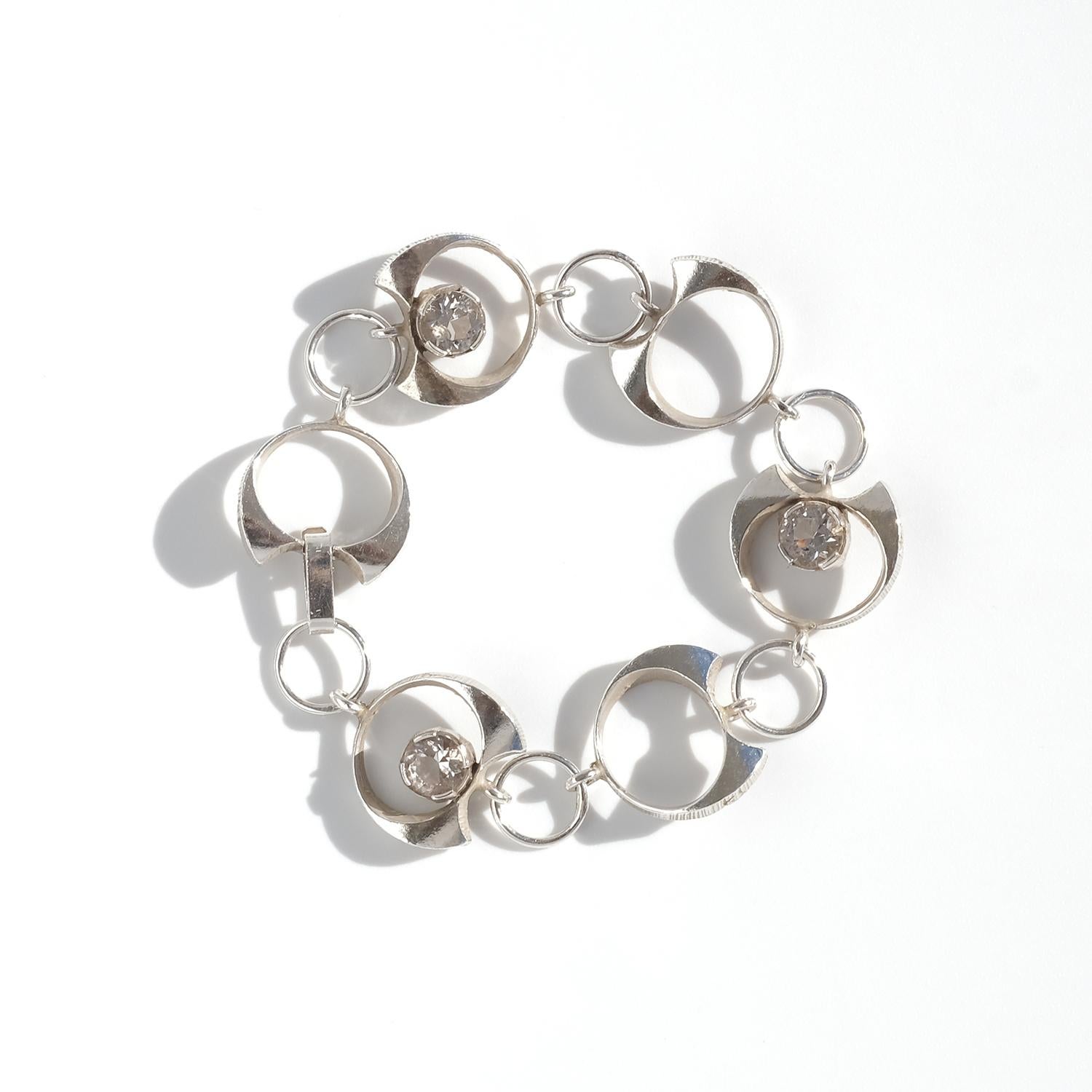 Dieses Armband im Vintage-Stil ist aus Silber mit Bergkristallen gefertigt und besticht durch sein raffiniertes, organisches Design. Das Armband besteht aus miteinander verbundenen kleinen Ringen, die größere halbmondförmige Silberringe mit