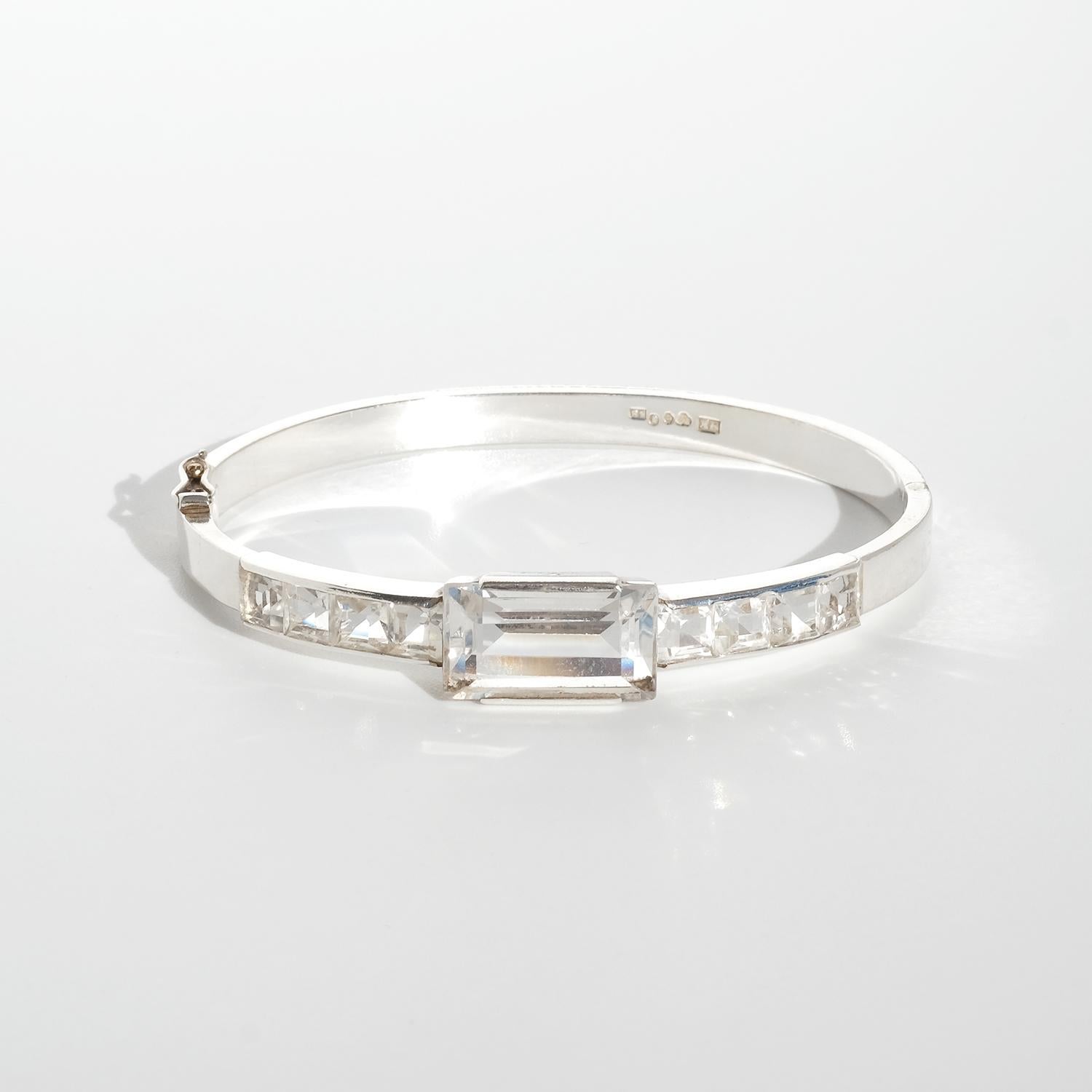 This vintage silver bracelet features a central row of nine rock crystal stones, with one large rectangular baguette-cut stone in the center, flanked by eight smaller square-cut stones, four on each side. The stones are set in a channel-style