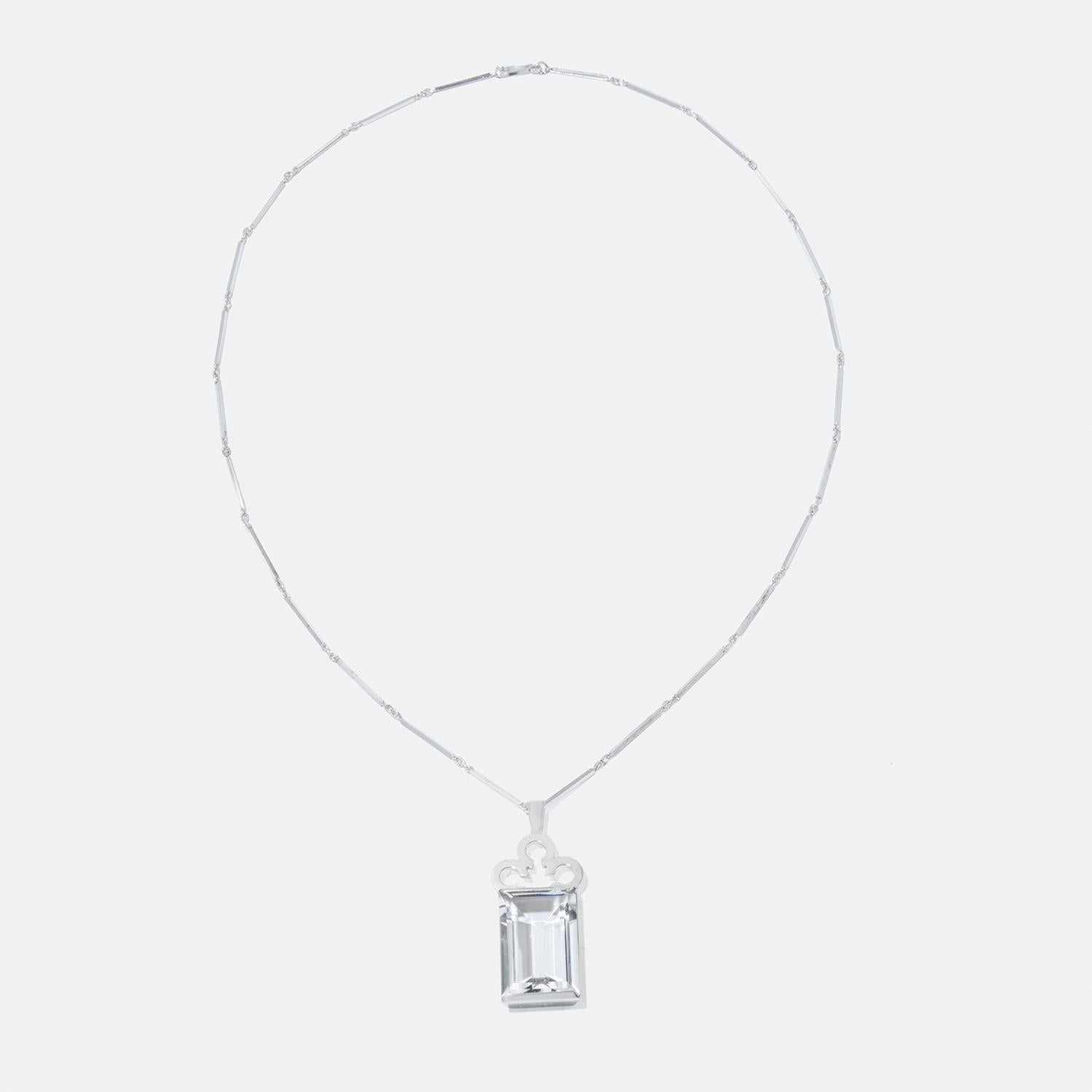 Questa elegante collana in argento presenta una lunga e delicata catena con maglie rettangolari sottili e uniformemente distanziate. Al centro è appeso un grande ciondolo rettangolare in cristallo di rocca incastonato in una montatura d'argento. La