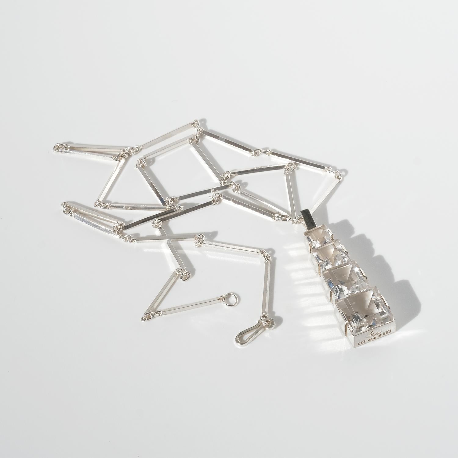 This vintage silver necklace features a striking pendant with stacked, graduated rock crystal cubes, creating a geometric, architectural effect. The pendant is suspended from a sleek bar and ring chain, composed of elongated silver rods connected by