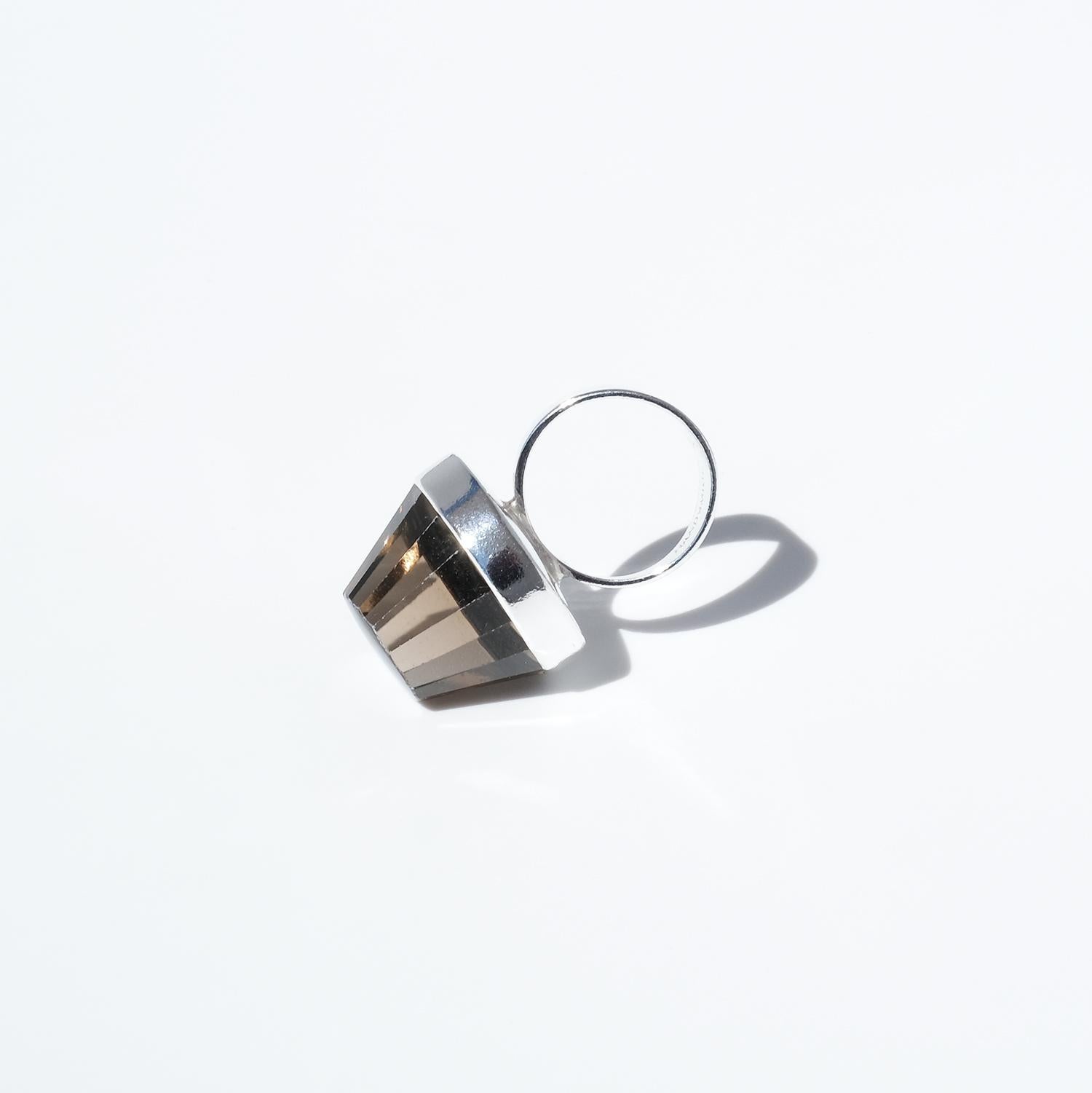 This vintage silver ring features a bold, round smoky quartz with a deeply ridged fluted cut, creating a striking interplay of light and shadow. The quartz shifts from deep smoky brown to a soft golden-brown depending on the light, enhancing its