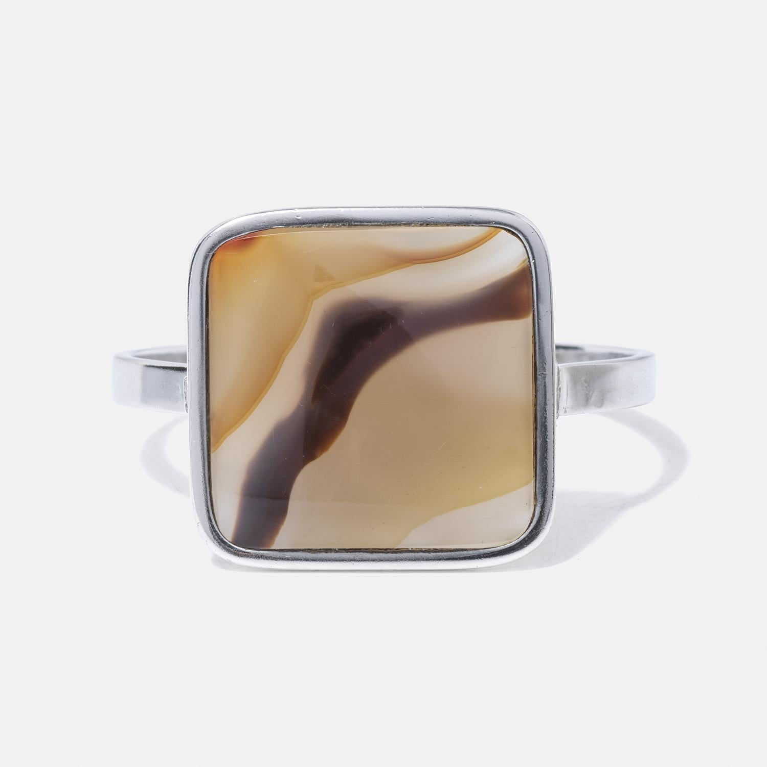Dieses elegante Armband zeigt einen quadratischen Tigerauge-Stein, der in Sterlingsilber gefasst ist und dessen faszinierende Schattierungen von Goldbraun, Beige und dunklen Streifen sich im Licht verändern. Das Band ist schön dünn, betont den Stein