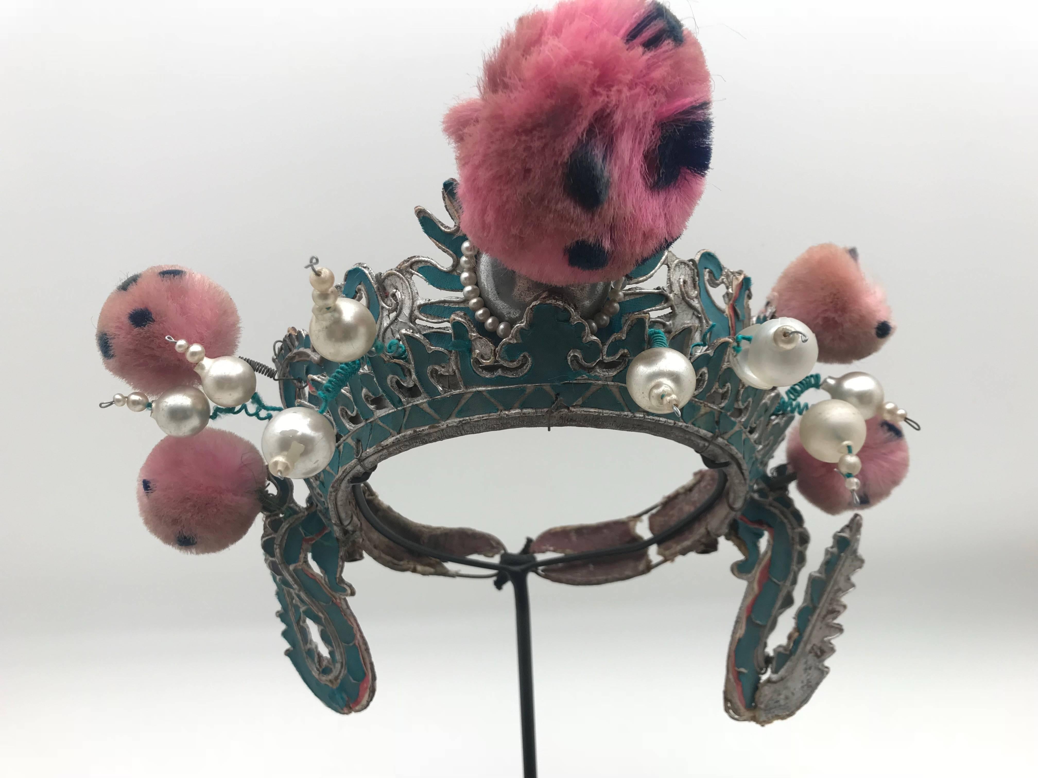 Vintage Chinese opera theatre headdress in turquoise and silver colors with pink and blue pom poms, early 20th century, mounted on a custom, black painted metal base.