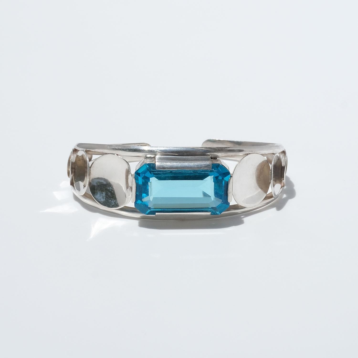 This silver cuff bracelet is adorned with a rectangular turquoise stone, and along its sides run round silver discs of various sizes.

The bracelet has a summery feeling and will be a perfect match to a classic summer-dress.

Dimensions: inner