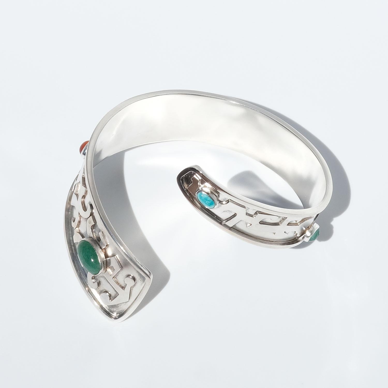 This silver armlet is decorated with something that resembles the ancient Egyptian sacred written symbols hieroglyphics and different stones such as, an aventurine quartz, a carnelian, a tiger eye stone, a malachite and a turquoise.

The design of
