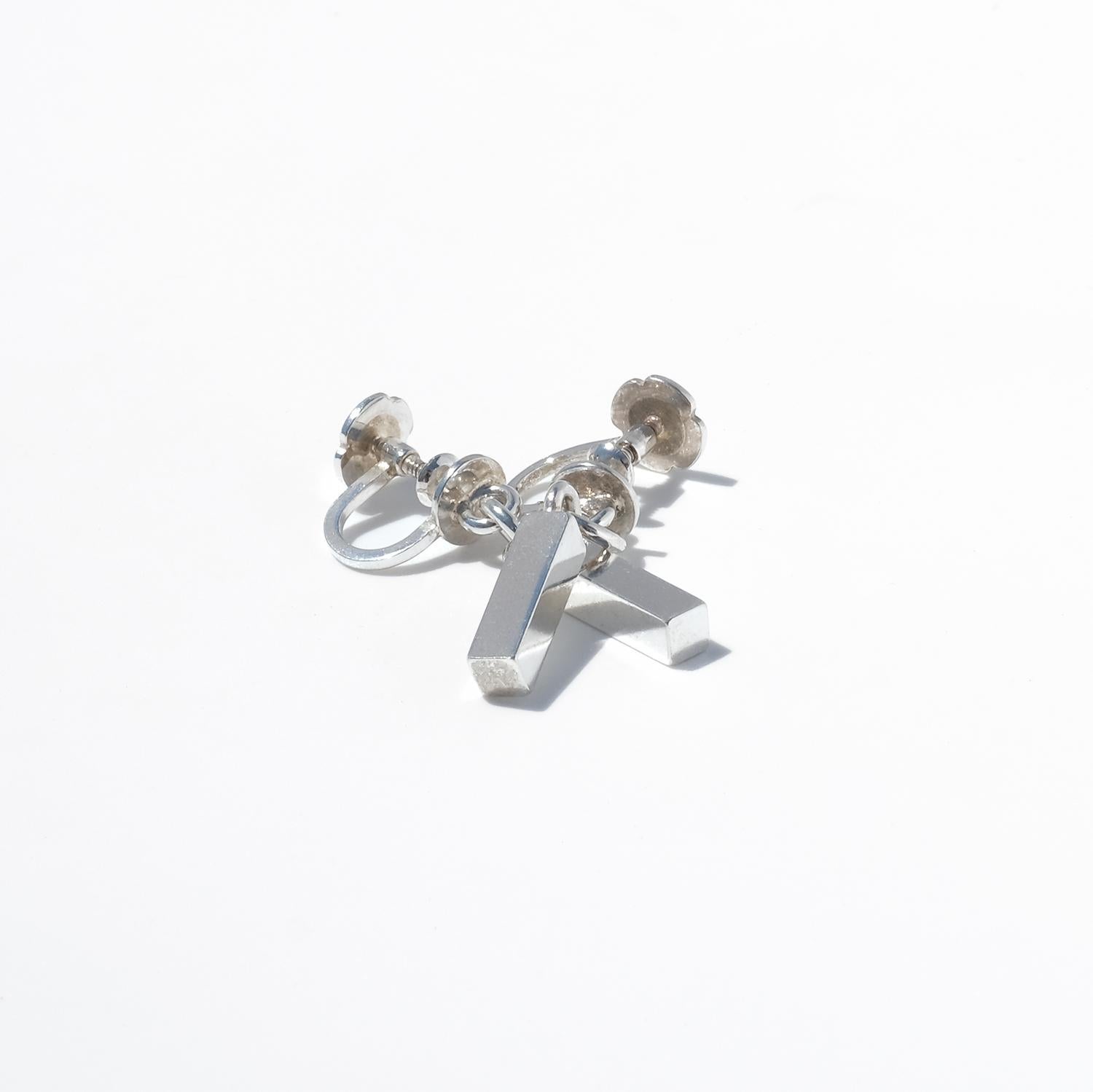 These classic silver bar earrings exude understated elegance with their sleek, straight form. They dangle gracefully from the ear, providing a subtle movement that catches the light. The earrings are designed with screw backs, a popular and secure