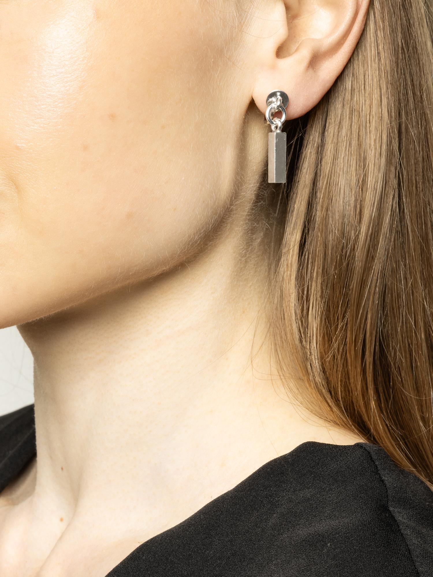 These classic silver bar earrings exude understated elegance with their sleek, straight form. They dangle gracefully from the ear, providing a subtle movement that catches the light. The earrings are designed with screw backs, a popular and secure