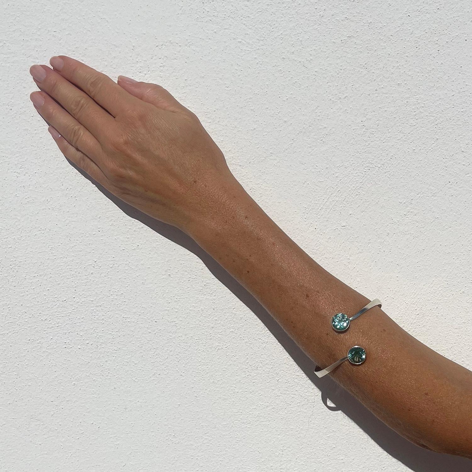 This silver cuff bracelet is adorned with two synthetic spinels. The spinels have an intensive turquoise colour and are typical eye-catchers.

The cuff bracelet has an oriental style. It is stretchy and is meant to be worn on the forearm.

It will