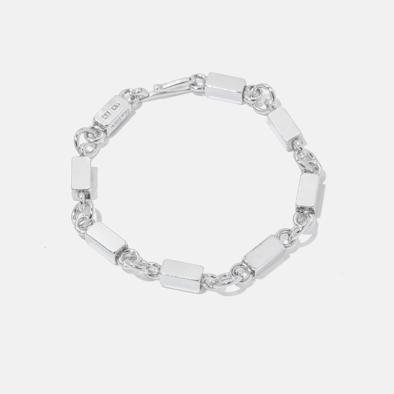 This sterling silver bracelet features a series of rectangular bars and circular rings, creating a seamless, flowing design. The sleek, geometric form of the bars contrasts beautifully with the smooth, round rings, enhancing its elegant simplicity.