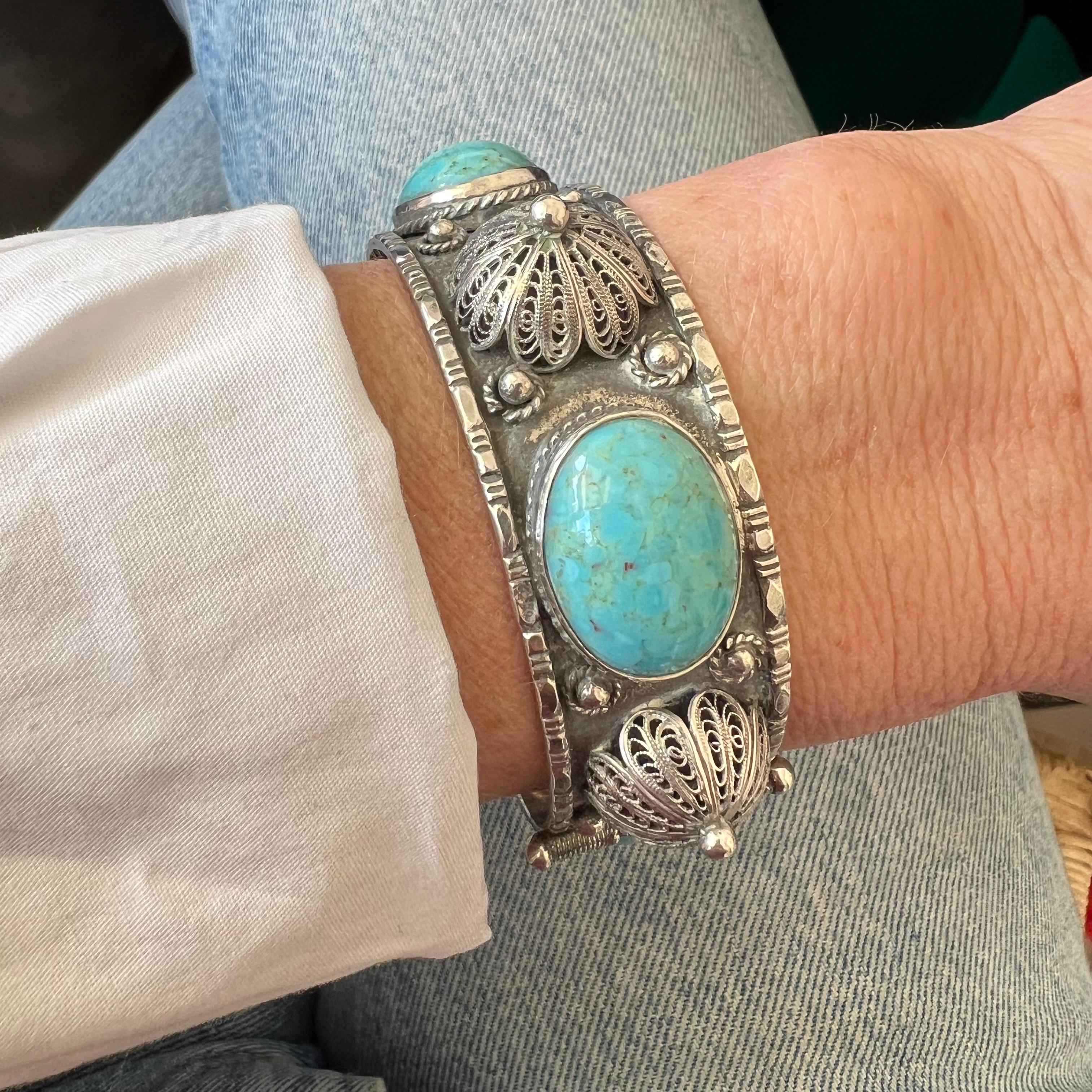 This vintage silver bracelet is an elegant and timeless piece of jewelry, beautifully showcasing the harmonious blend of natural stones and intricate metalwork. The bracelet features four oval turquoise stones, each set in a bezel setting that