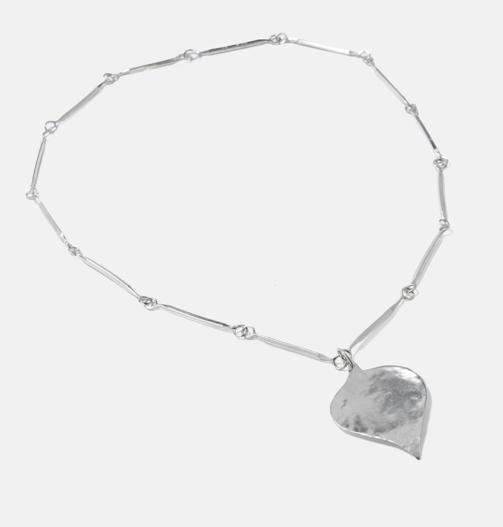 A typical 1970s piece of jewelry. The chain is made of 14 angular pools connecting with each other with round rings. The leaf has a hammered surface. Bengt Liledahl (1932-) is one of Swedens most renowned silversmith and his career has spun over