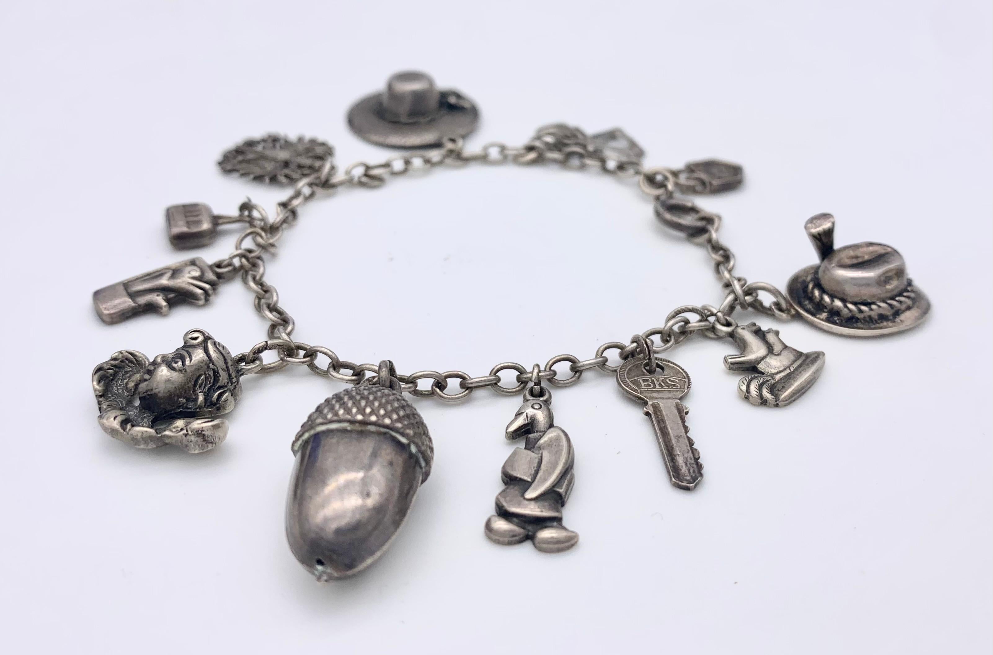 This Austrian silver charm bracelet features 12 different charms. A padlock, faith, hope and charity as one charm, a ladies hat, the Austrian eagle, a gondola, a birds box, a putto, an acorn powerful charm against thunder and lightning (with a dent)