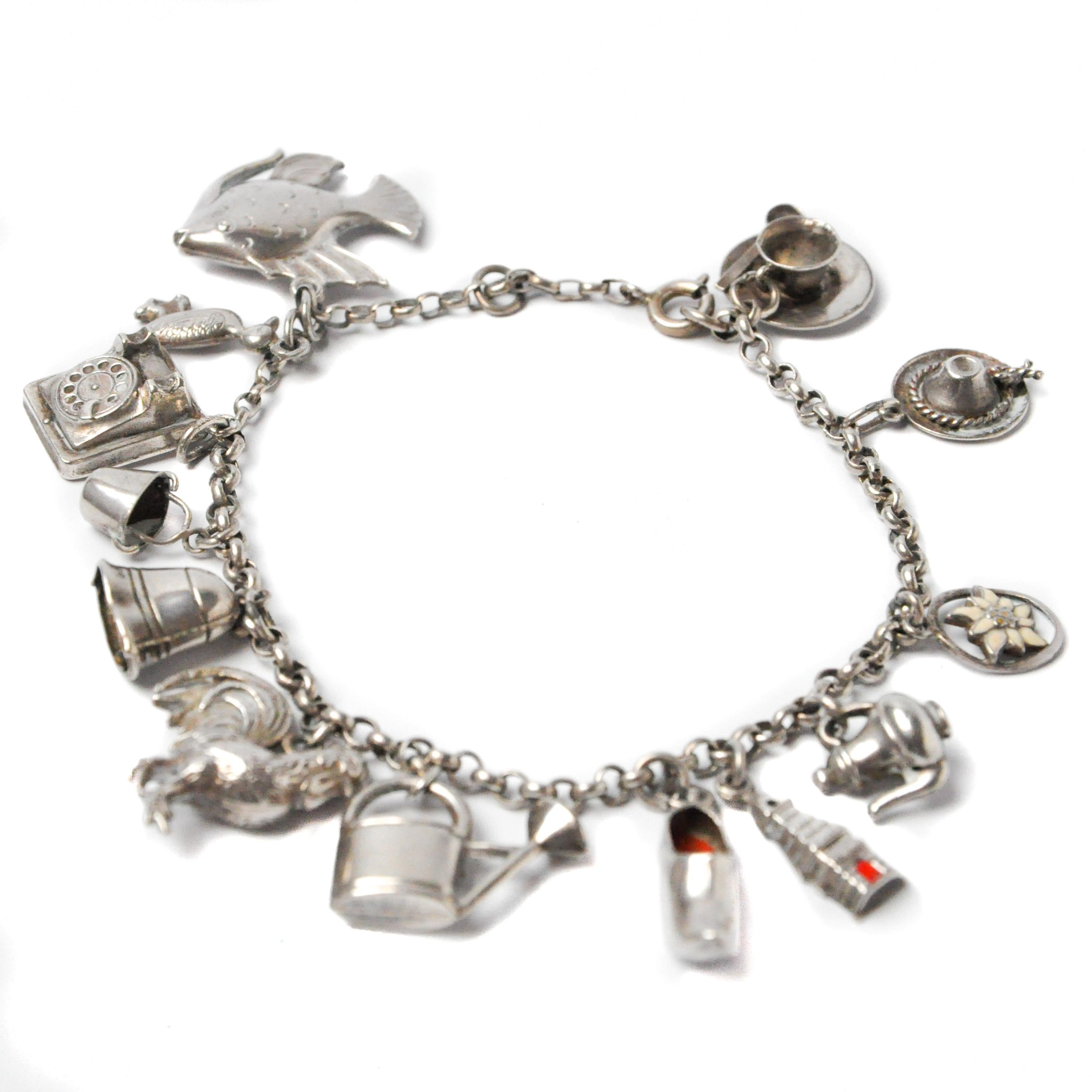 Beautiful vintage silver charm link bracelet from around 1940's with thirteen antique charms. A tea cup, hat, flower, tea pot, house, wooden shoe, watering can, rooster, bell, bucket, phone, duck and a fish. The wooden shoe and house have a red