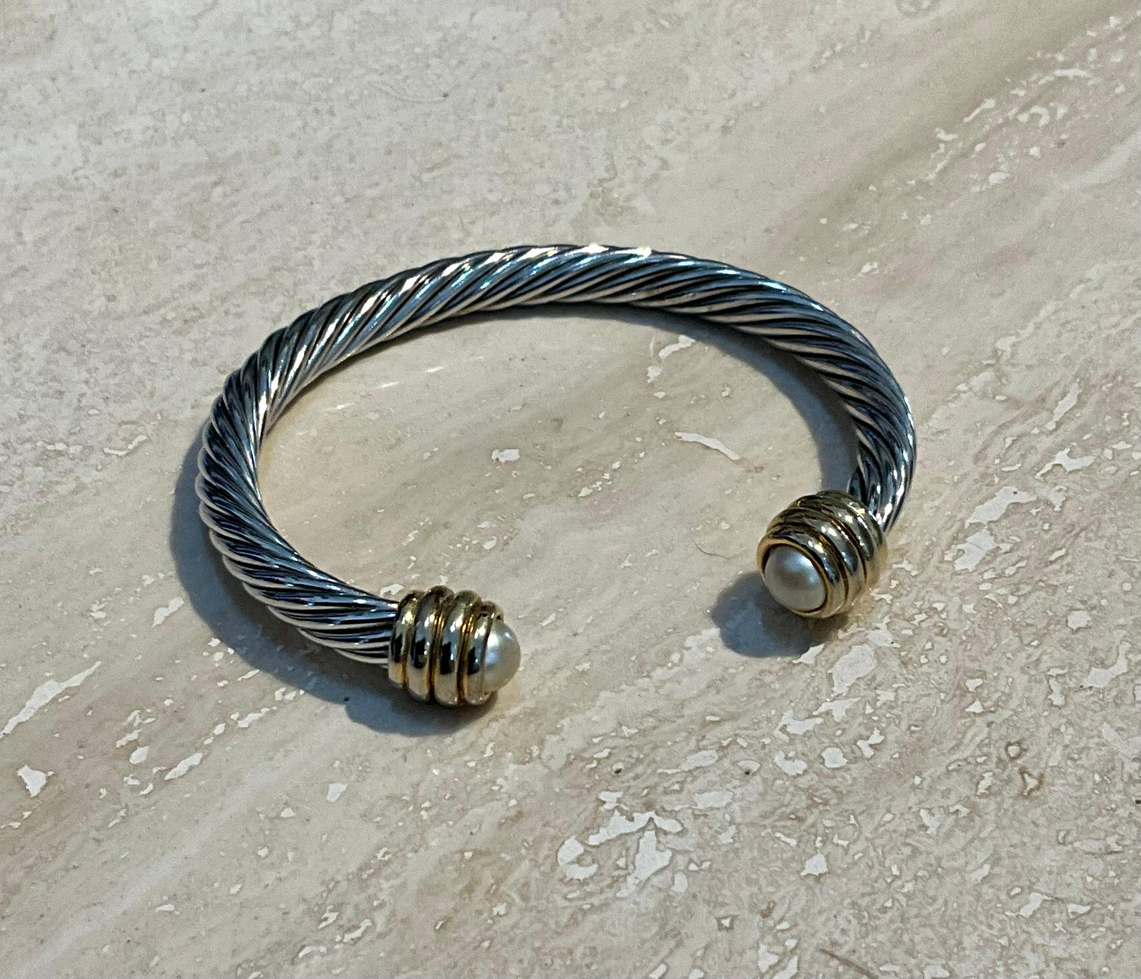 Questo bracciale classico a cavo in argento vintage con accenti di perle è un gioiello senza tempo che unisce l'eleganza della lavorazione dell'argento alla bellezza classica degli accenti di perle. La combinazione del design a cavo con le perle