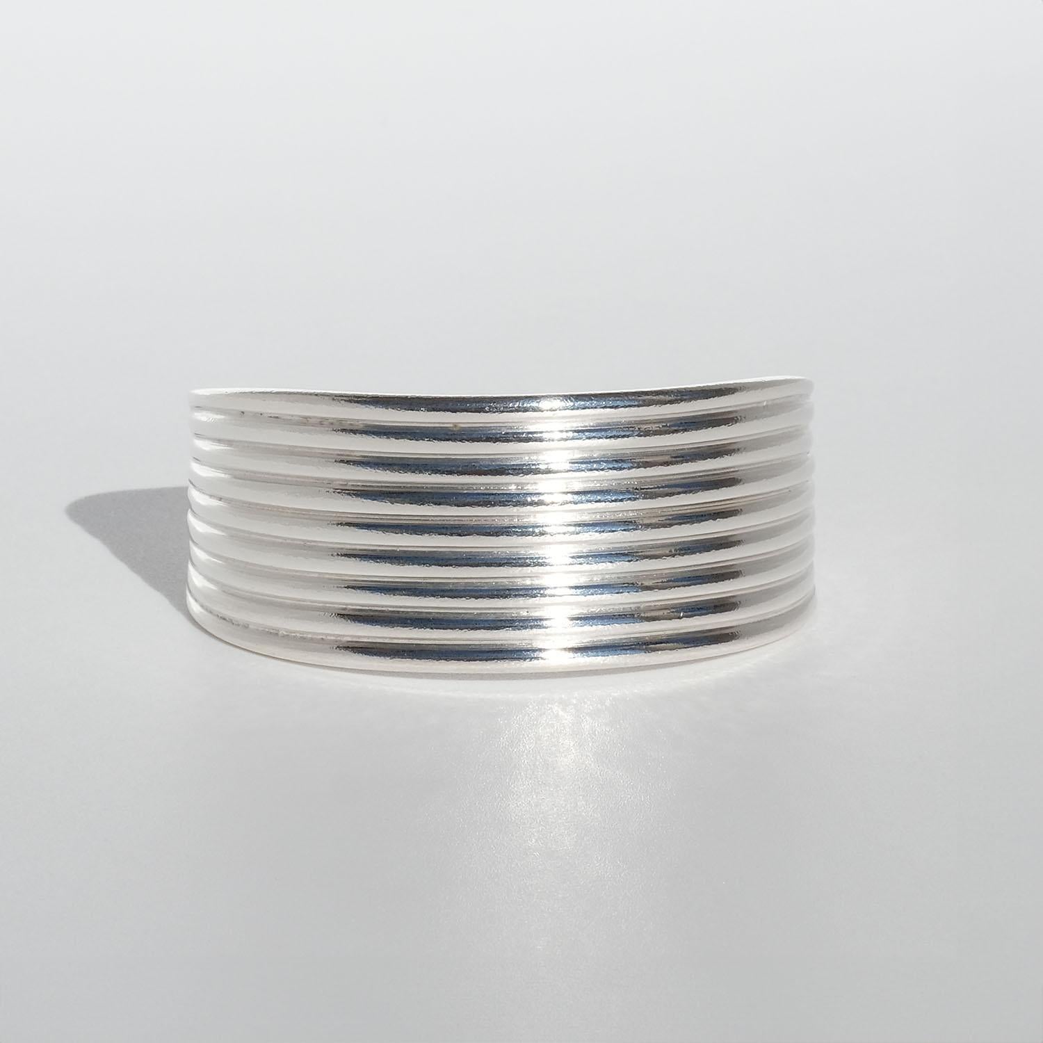 This silver cuff bracelet has a shiny, textured surface. Its shape can be described as simple and on point and it looks like something a roman warrior would wear.

The cuff bracelet radiates elegance and is a great example of timeless jewelry. It is