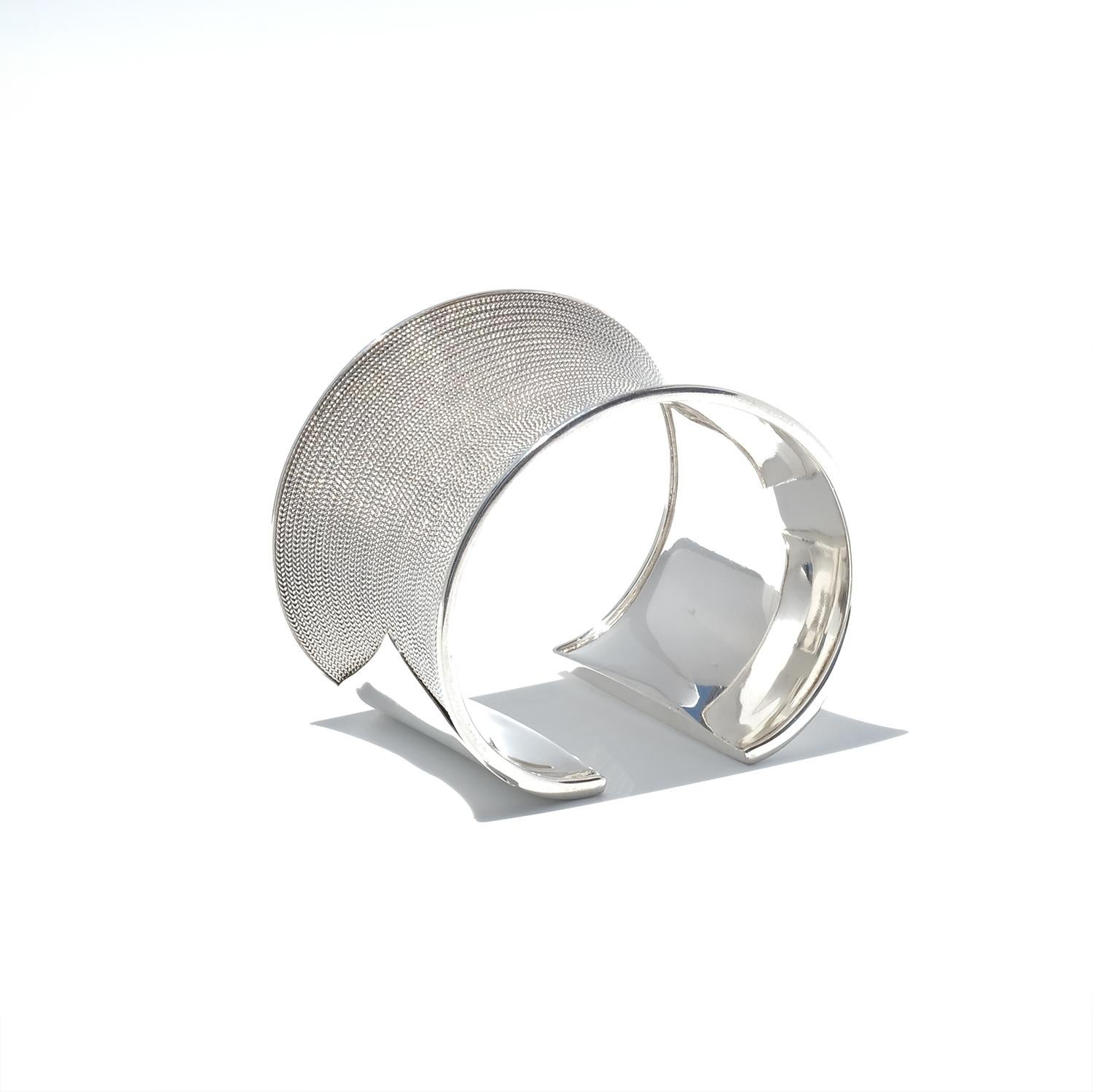 Dieses silberne Manschettenarmband im Vintage-Stil weist auf der Außenseite ein kompliziertes, fein gewebtes Muster auf, das an eine Rüstung erinnert, und auf der Innenseite eine polierte Oberfläche. Seine gewellte Form und seine beachtliche Breite
