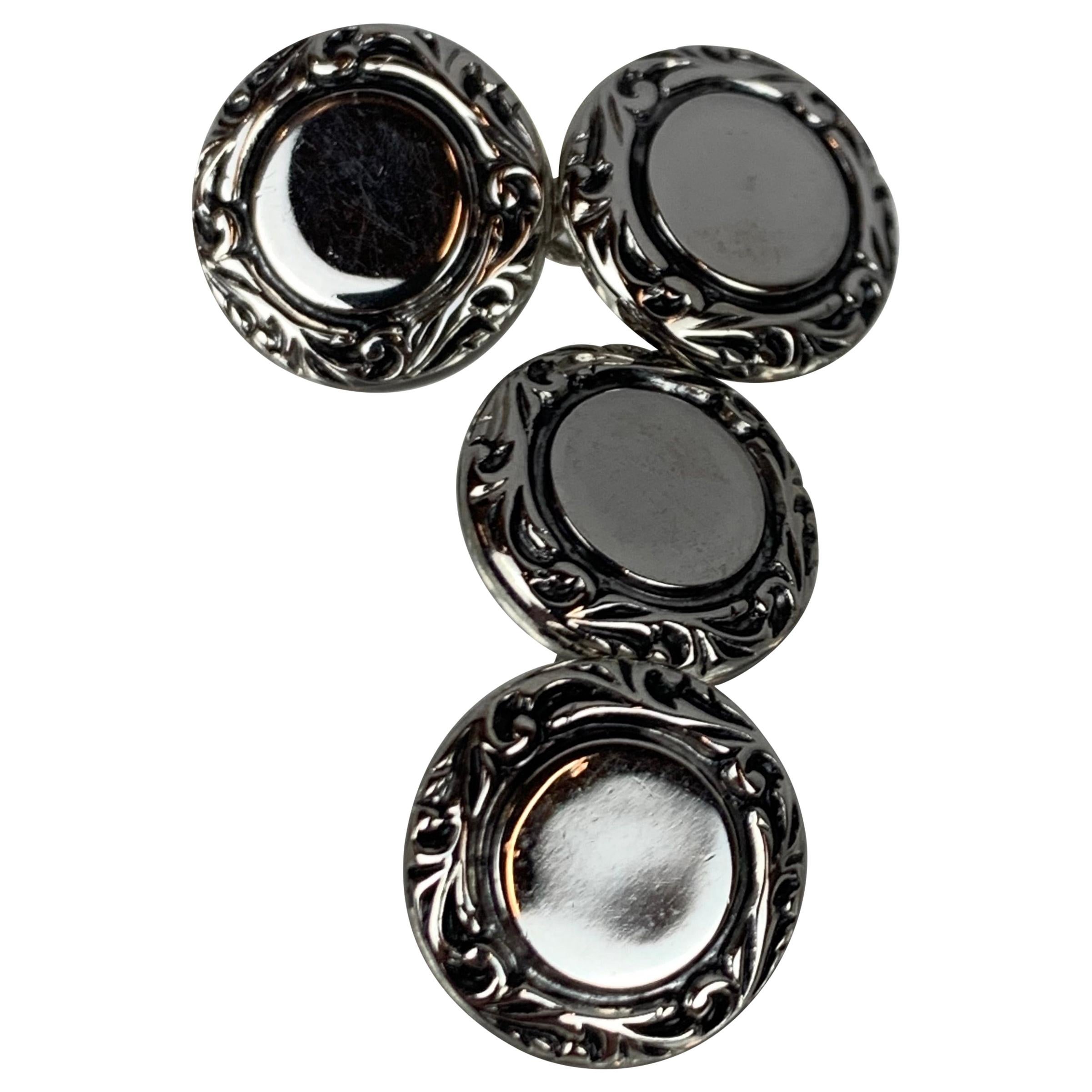 A Pair of vintage silver tone double round cufflinks.   The scrolled border surrounds a flat central plateau.  The round discs are connected by small chains.  Their size makes them easy to slip into french cuff shirts.
Measurements-disc to disc  1