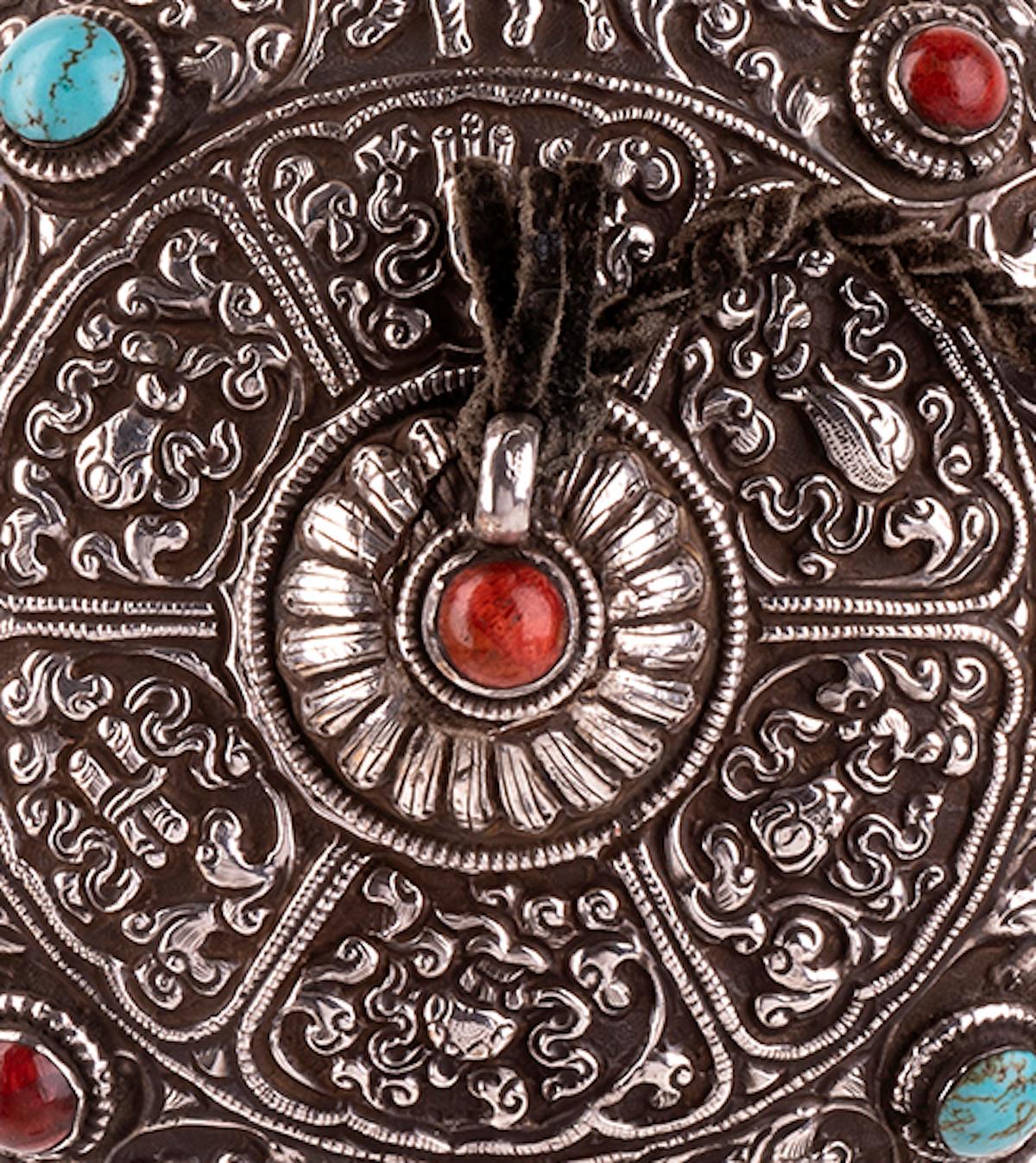 This silver flask is a precious decorative object to smell the tobacco, realized in Tibet in the first half of the 20th century.

Round shaped with central opening, chased and embossed with good luck symbols and set with turquoise and coral