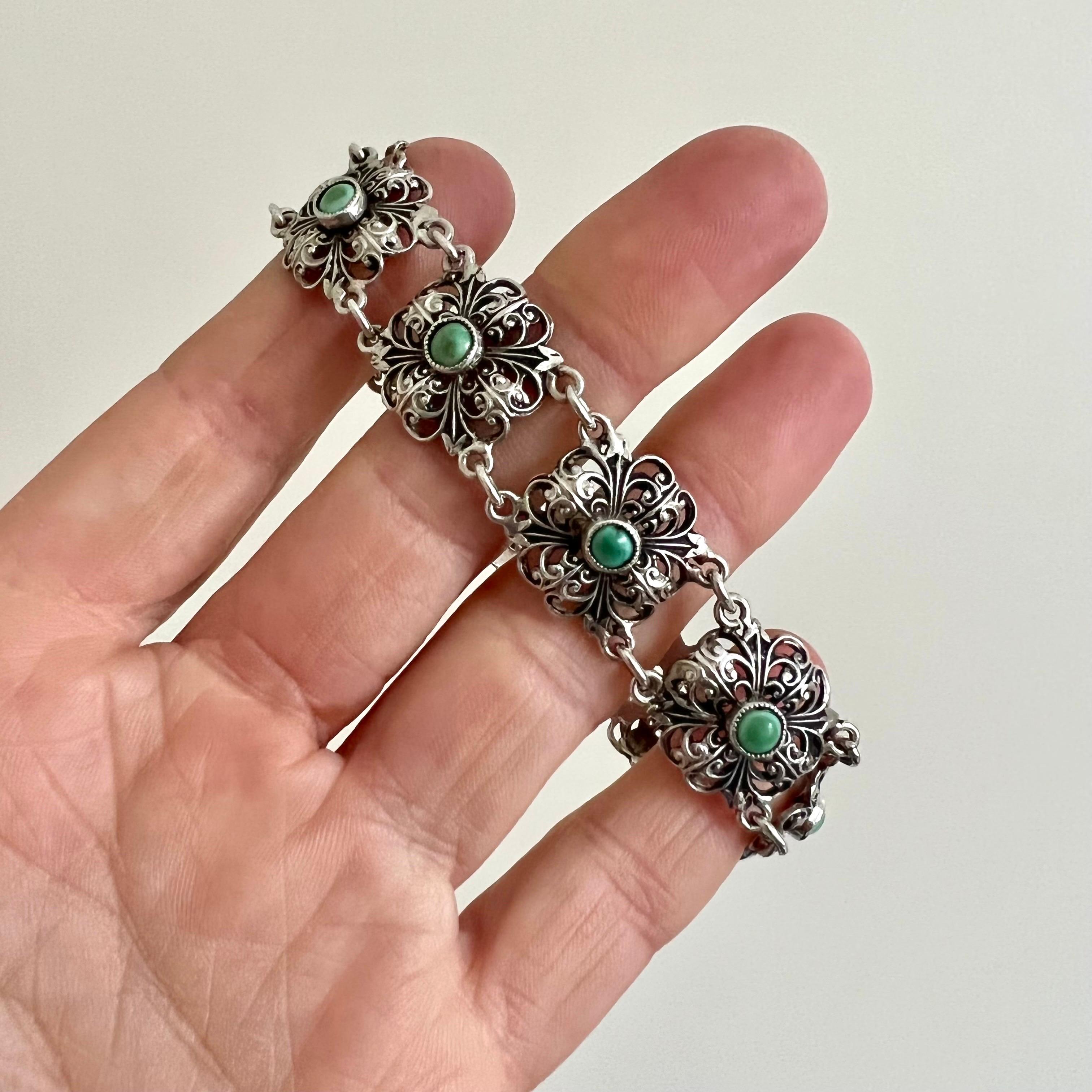 Magnifique bracelet ajouré en argent du début du 20e siècle, serti de neuf turquoises vertes. Le bracelet est composé de neuf délicats compartiments floraux en argent, chaque maillon étant serti d'une pierre turquoise verte ronde au centre. Ces