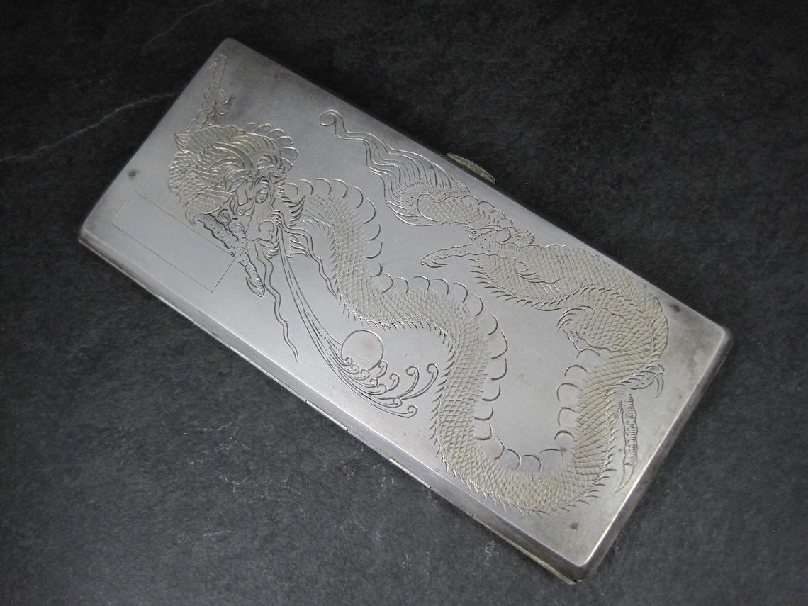 This gorgeous silver cigarette case features a hand chased/engraved dragon and an area for a monogram.
The inside is gilt with gold.

Measurements: 3 1/8 by 6 3/4 inches
Weight: 196.7 grams
Hallmarks: Silver, Chinese hallmark

Condition: Excellent