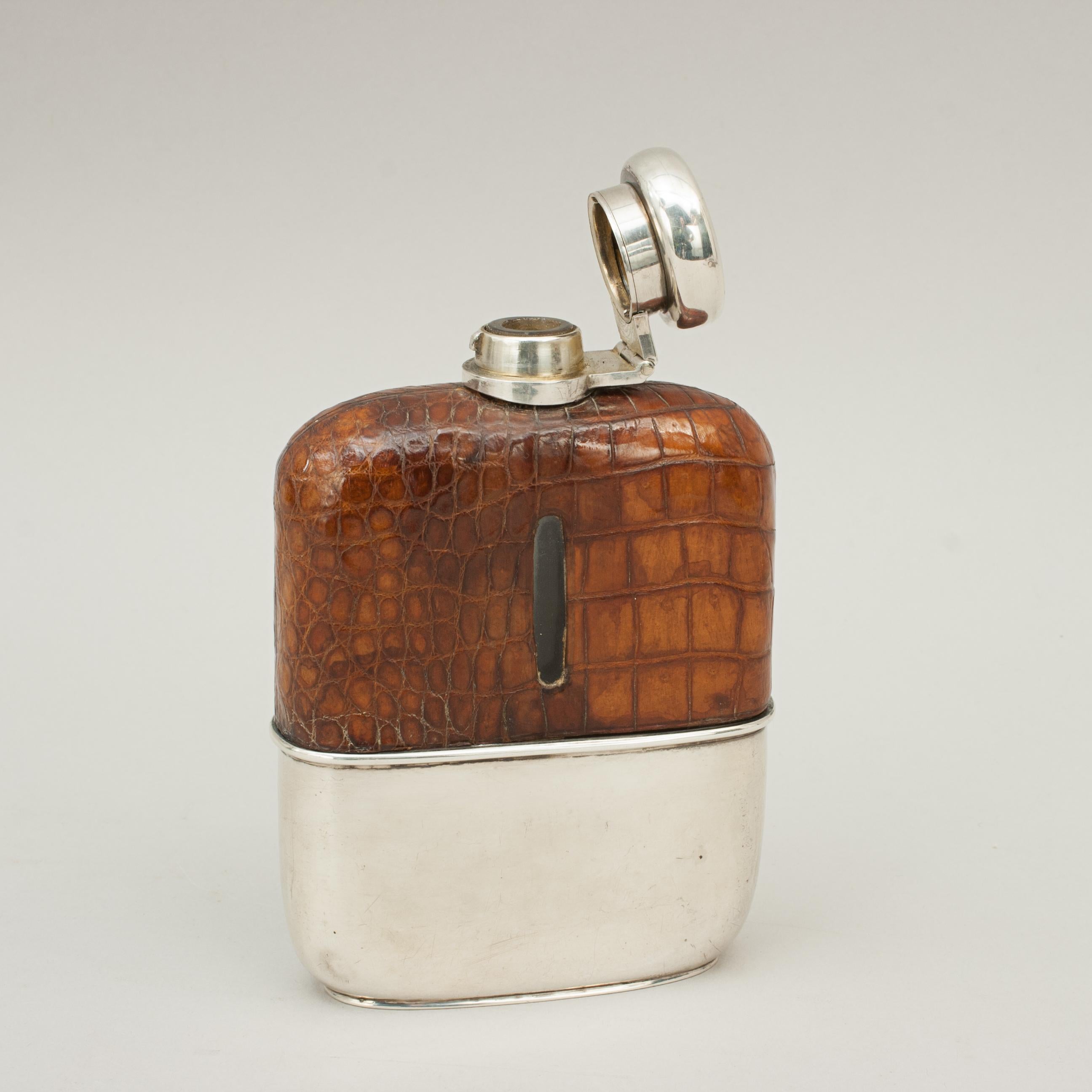 Leather and silver gentleman's hip flask.
A very nice silver spirit hip flask with the top half covered in leather with level viewing windows cut into both sides. The leather is embossed to look like crocodile skin, the flask with hinged silver lid