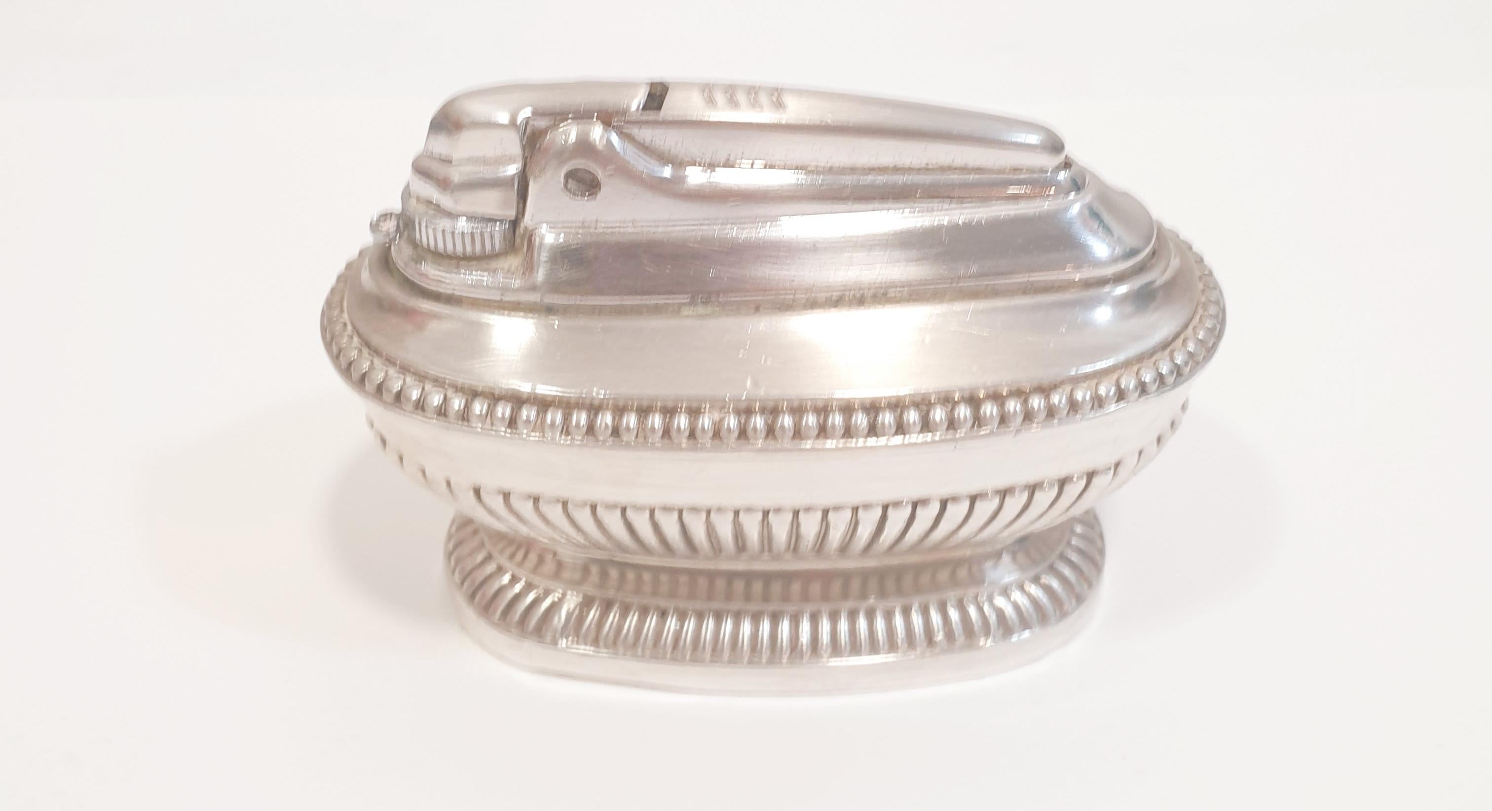 A vintage Ronson silver plated 'Queen Anne' table lighter, mid 20th century, the heavily weighted elongated oval lighter with bead and gadroon decoration upon a waisted base; mark of Ronson underside, height 6 cm, width 9 cm

PRADERA is a second