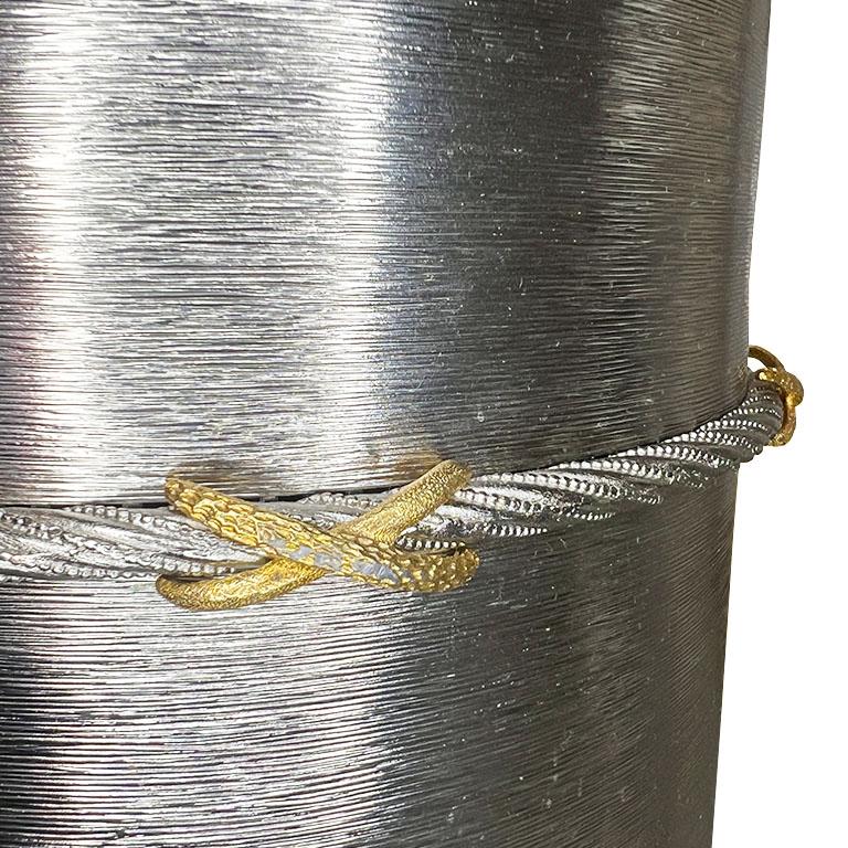A vintage post-modern metal wastebasket or trash can with ribbon detail. Add a little something unexpected to a powder room or office. This round trash bin is created from brush metal in a silver tone. A trompe l'oeil rope decorates around the