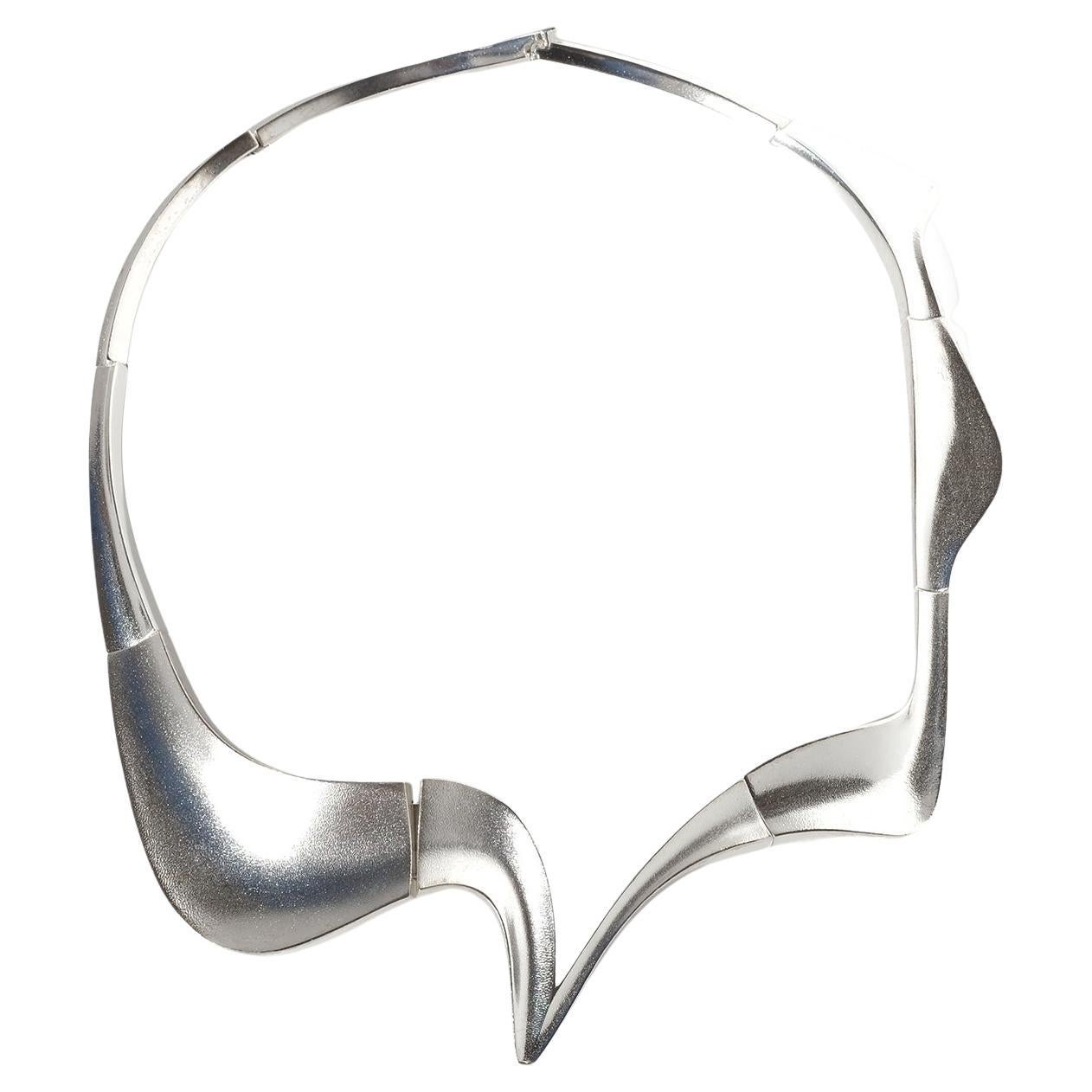 Questa collana d'argento vintage è caratterizzata da una forma scultorea che sale verso l'alto e incornicia la scollatura con un contorno fluido e asimmetrico. Ogni segmento è sagomato con una precisa transizione da superfici dolcemente curve a