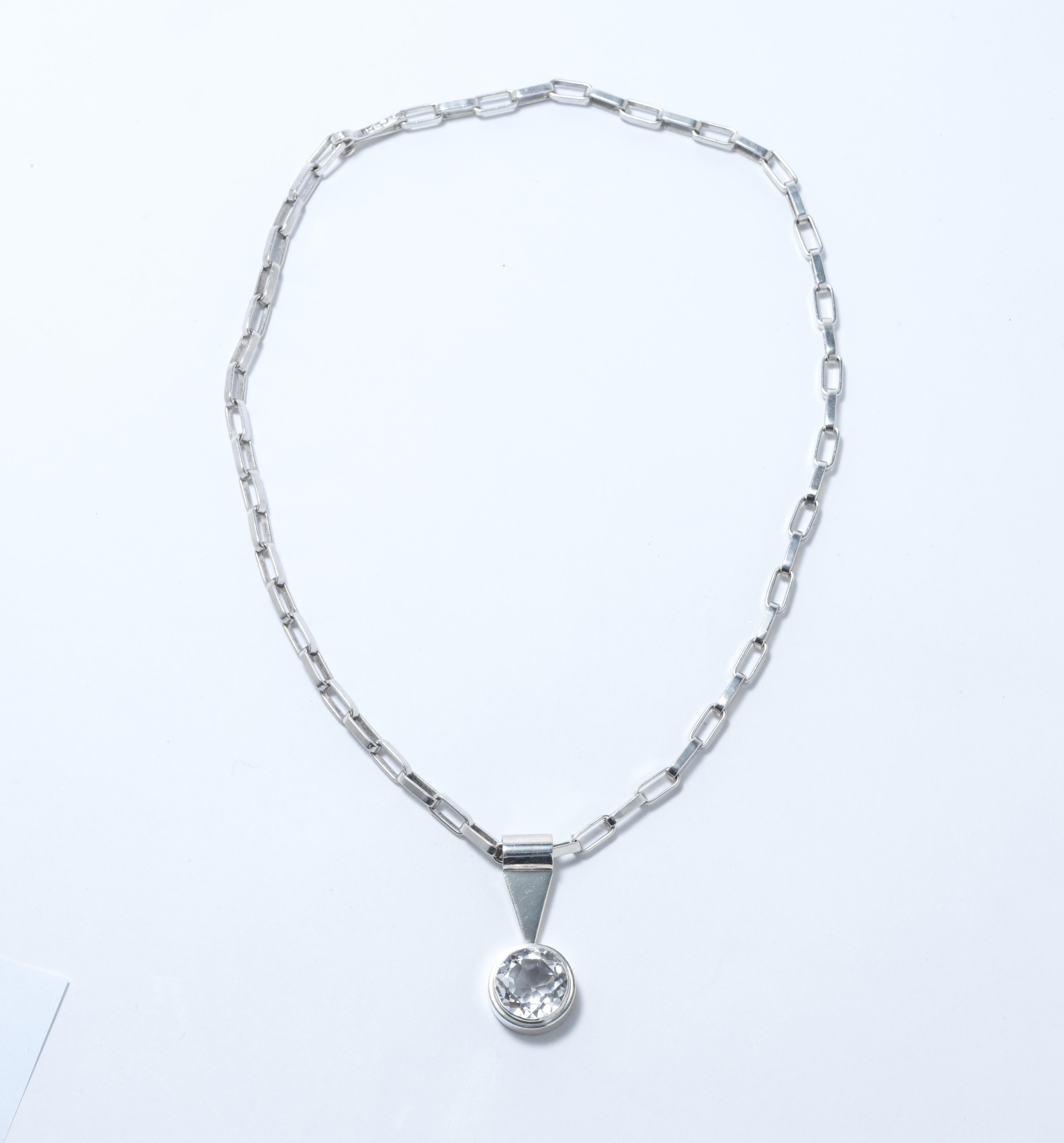 A silver necklace made in 1968 by the Swedish silver smith master Anders Högberg. He was at this time one of the most known smiths in Sweden. It has a strong chain with oval links on which a pendant hangs. The pendant, also made of silver,  has a