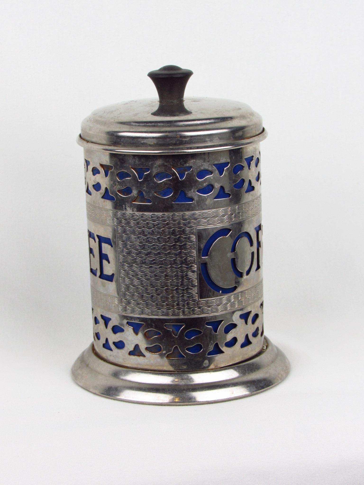 Vintage silver-plate coffee canister with filigree etchings and elegant cutouts, allowing the vibrant blue plastic insert to show through. Cutout of the word 