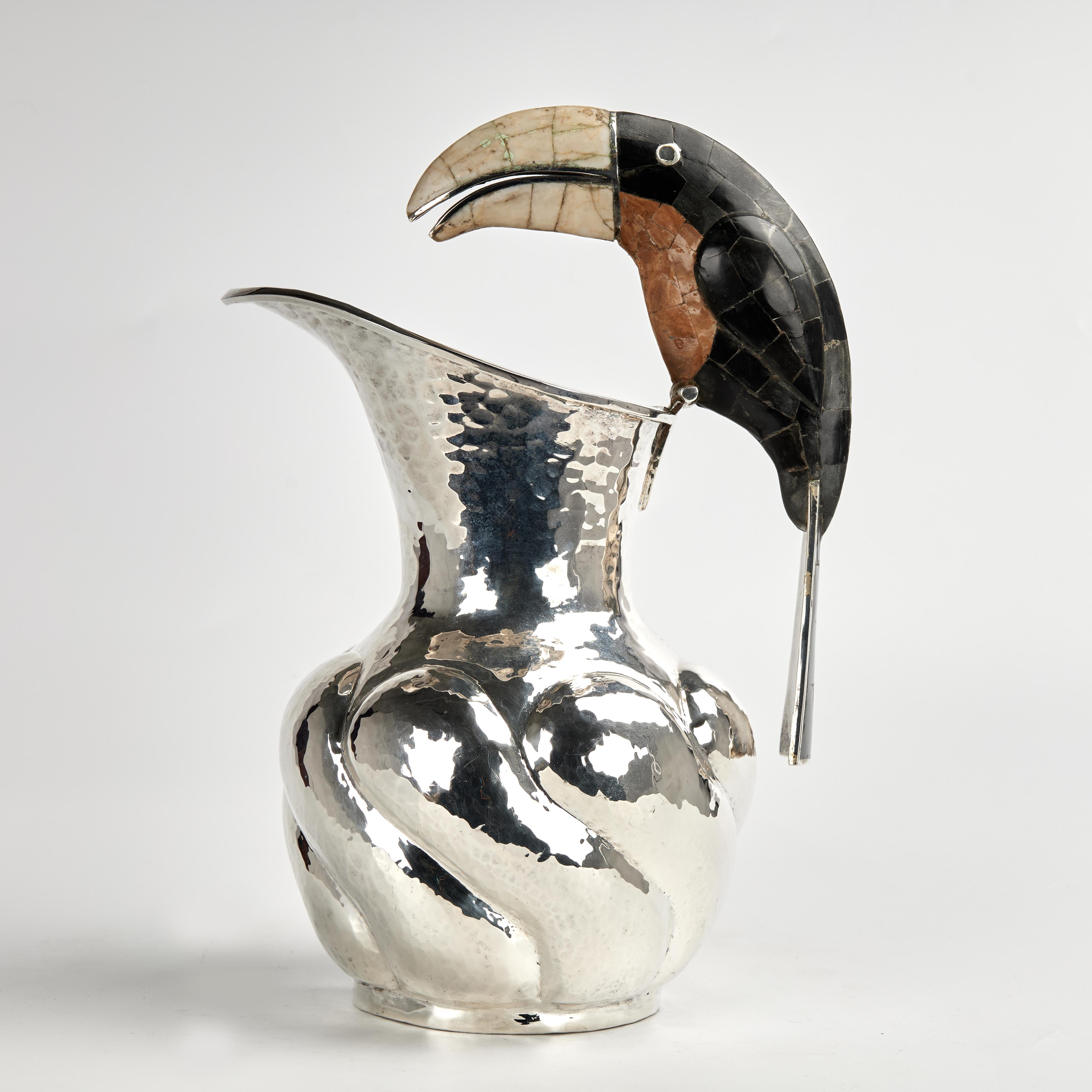 Standout mid century pitcher handcrafted in hammered copper with a silver plate finish in classic form featuring a stone clad toucan as a handle.