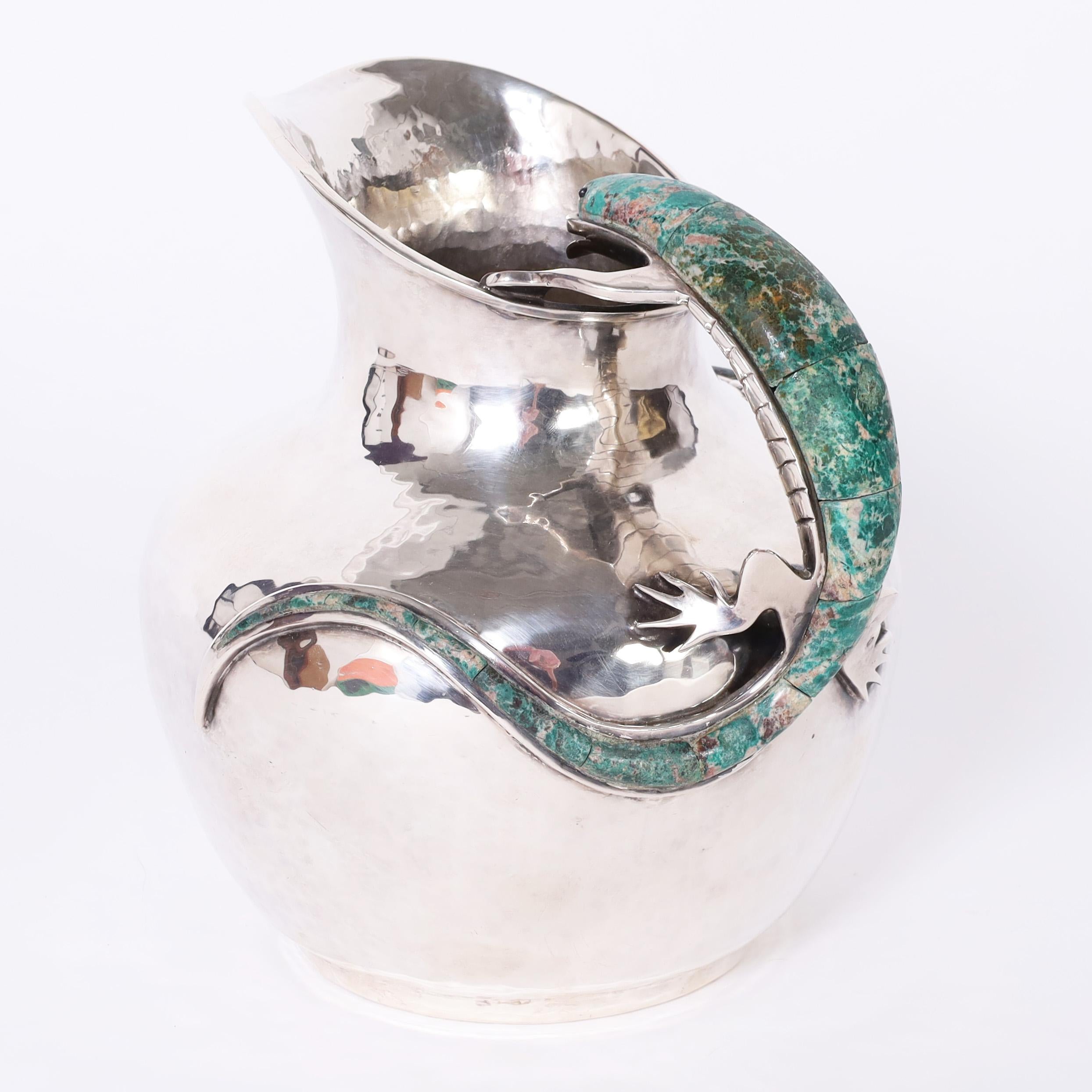 Standout modern form pitcher handcrafted in silver plate over hammered copper featuring a turquoise clad salamander or lizard as a handle and a smaller one attached to the side. Stamped Emilia Castillo Mexico on the bottom. 