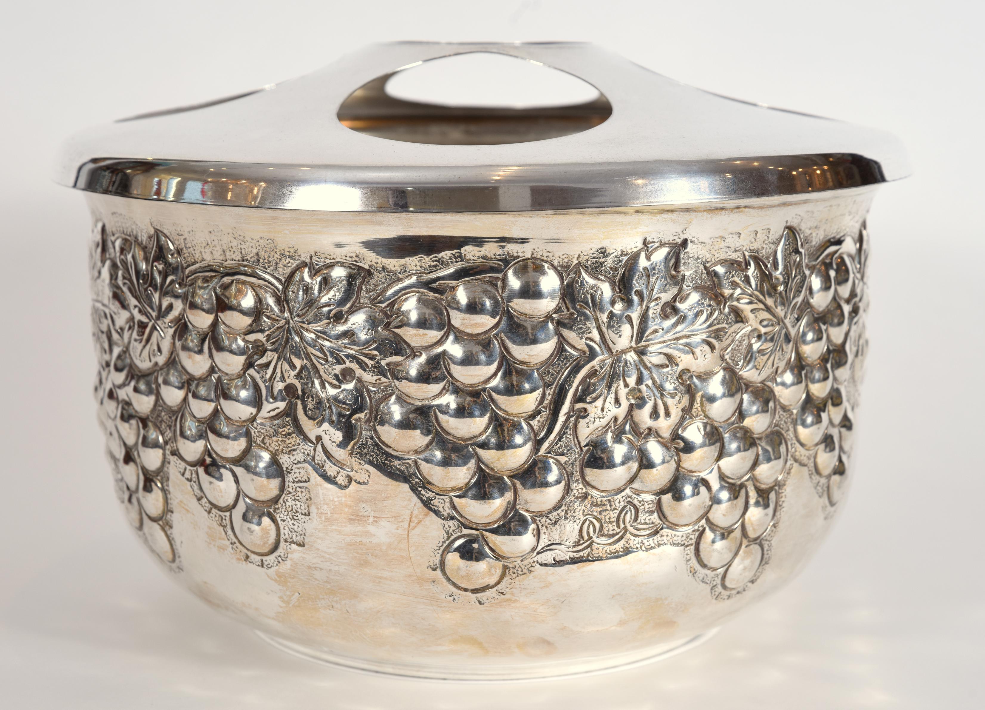 Exquisite silver plated round covered five bottles wine or champagne cooler or Ice bucket with intricate exterior decorative design motifs of grapes and vines. The round removable cover seat easily five bottles of wine or champagne. This barware or